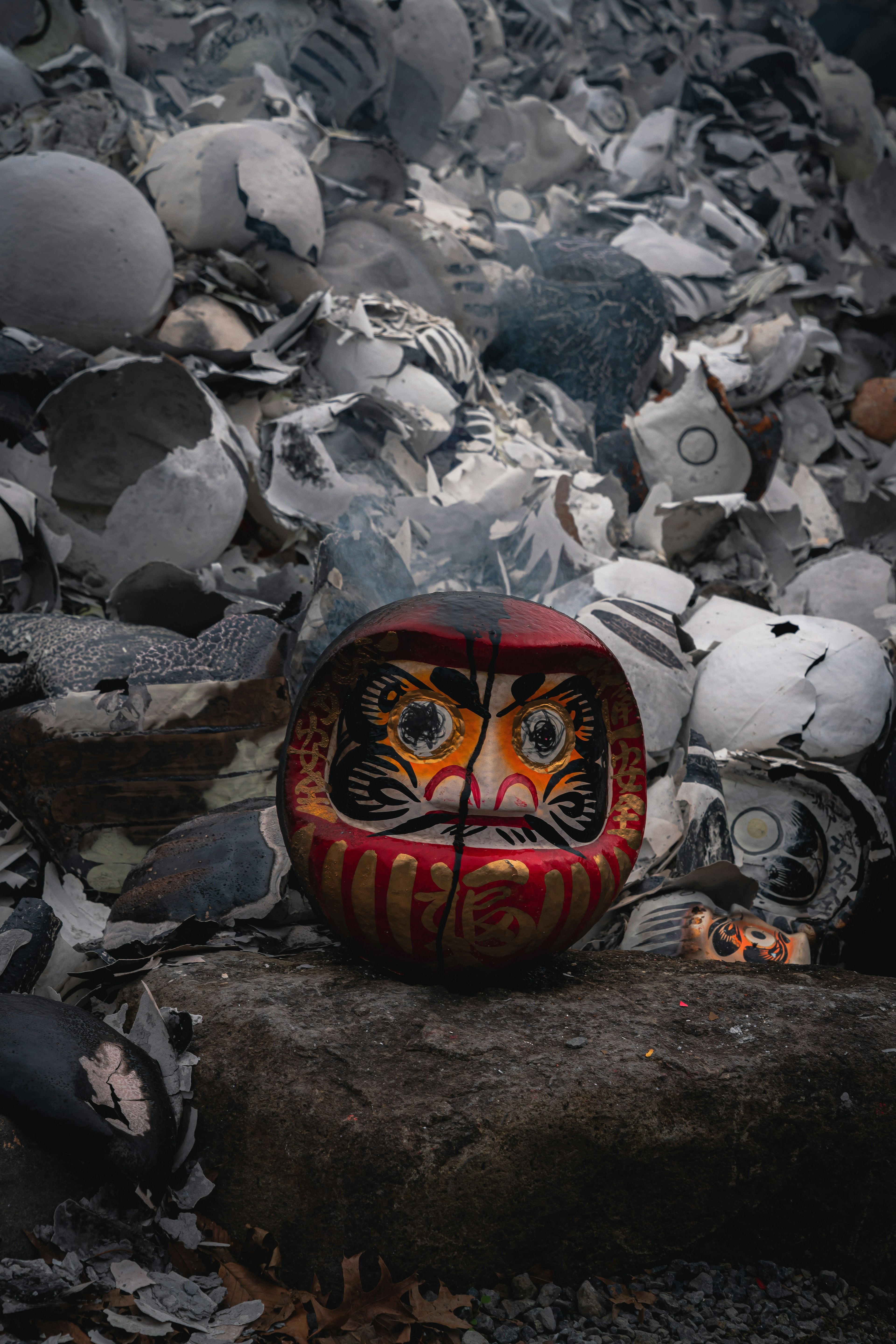 Une poupée daruma placée devant un tas de poterie brisée