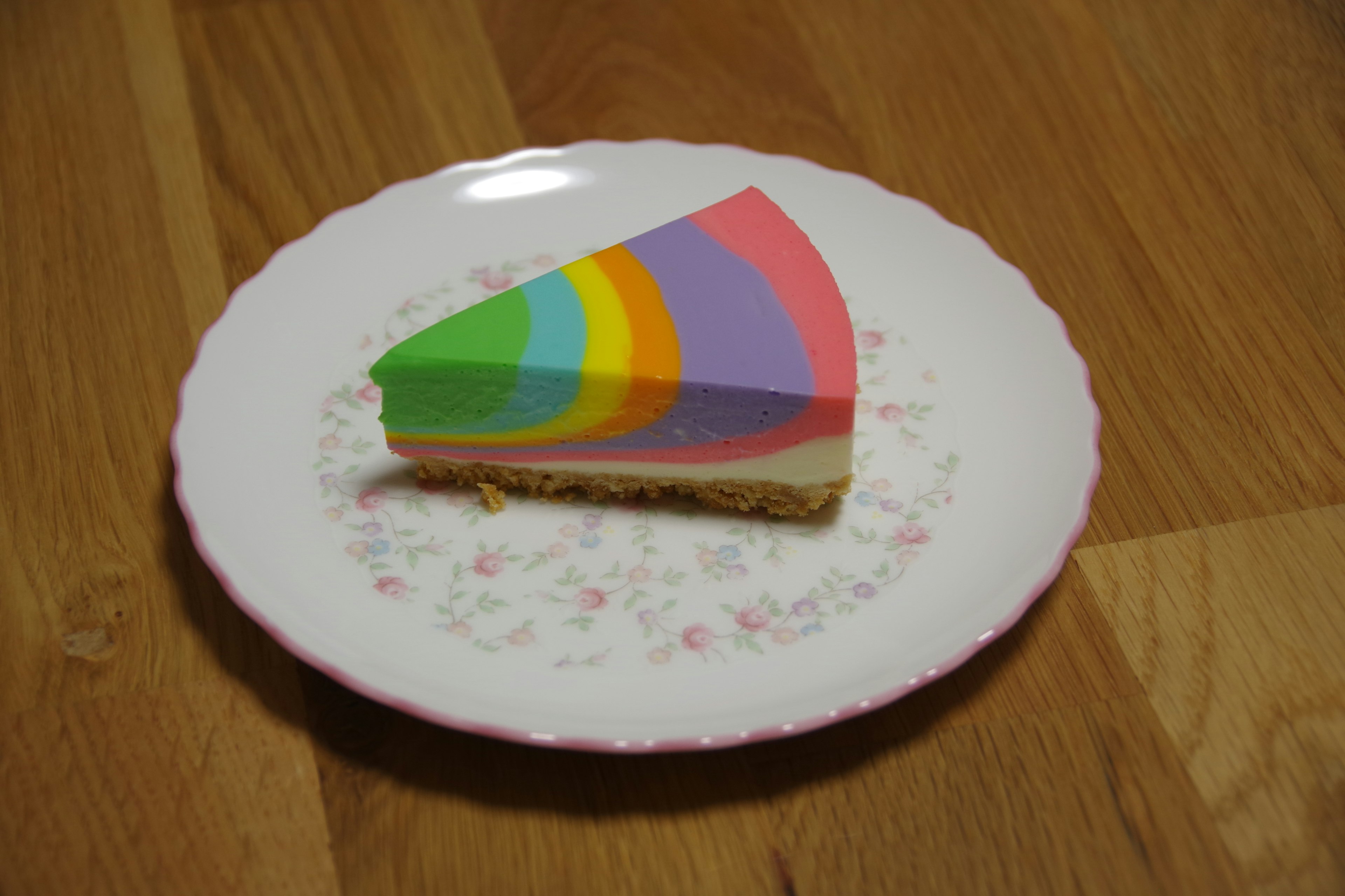 Una fetta colorata di torta arcobaleno su un piatto bianco