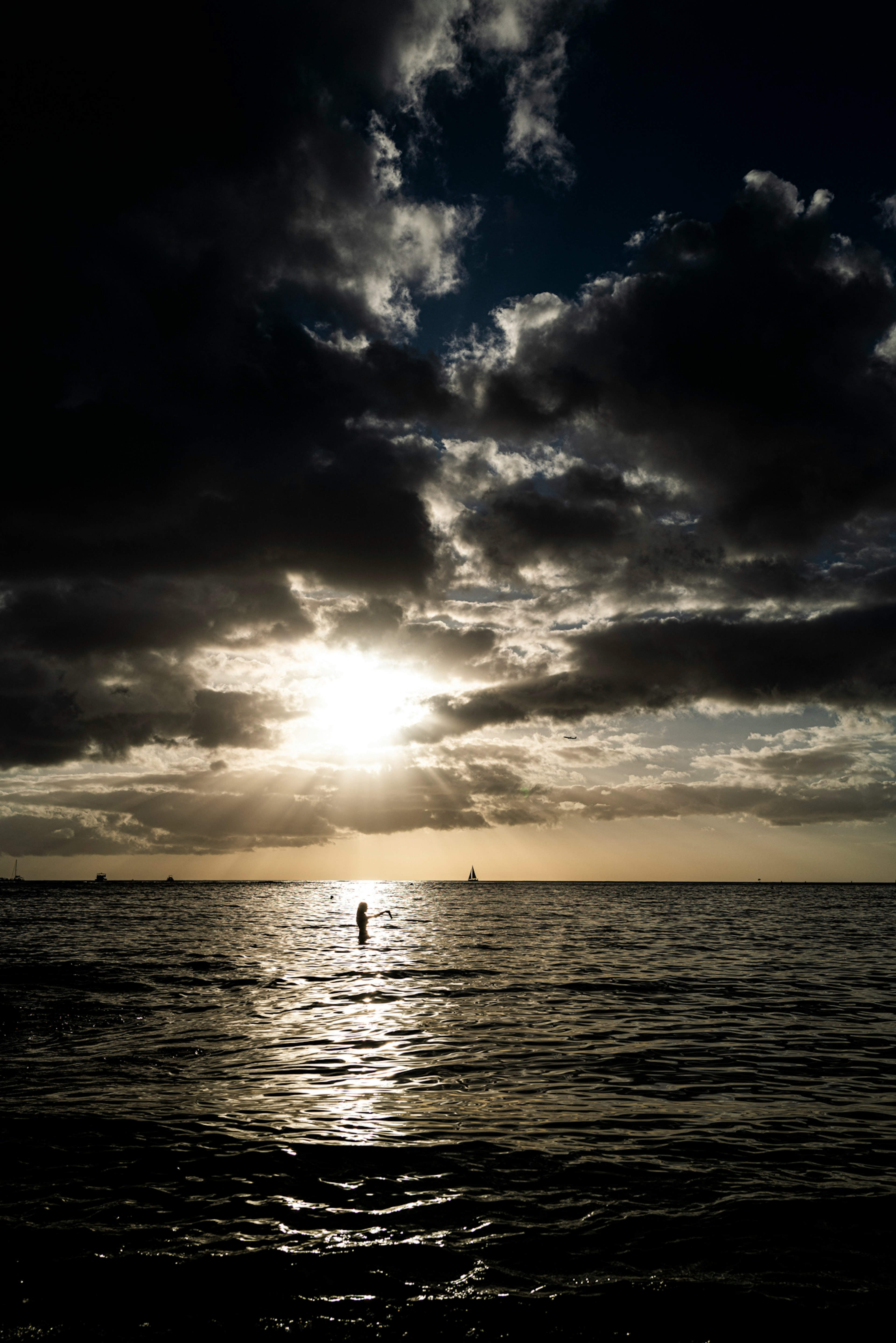 Silhouette einer Person im Ozean mit Sonnenuntergang und Wolken