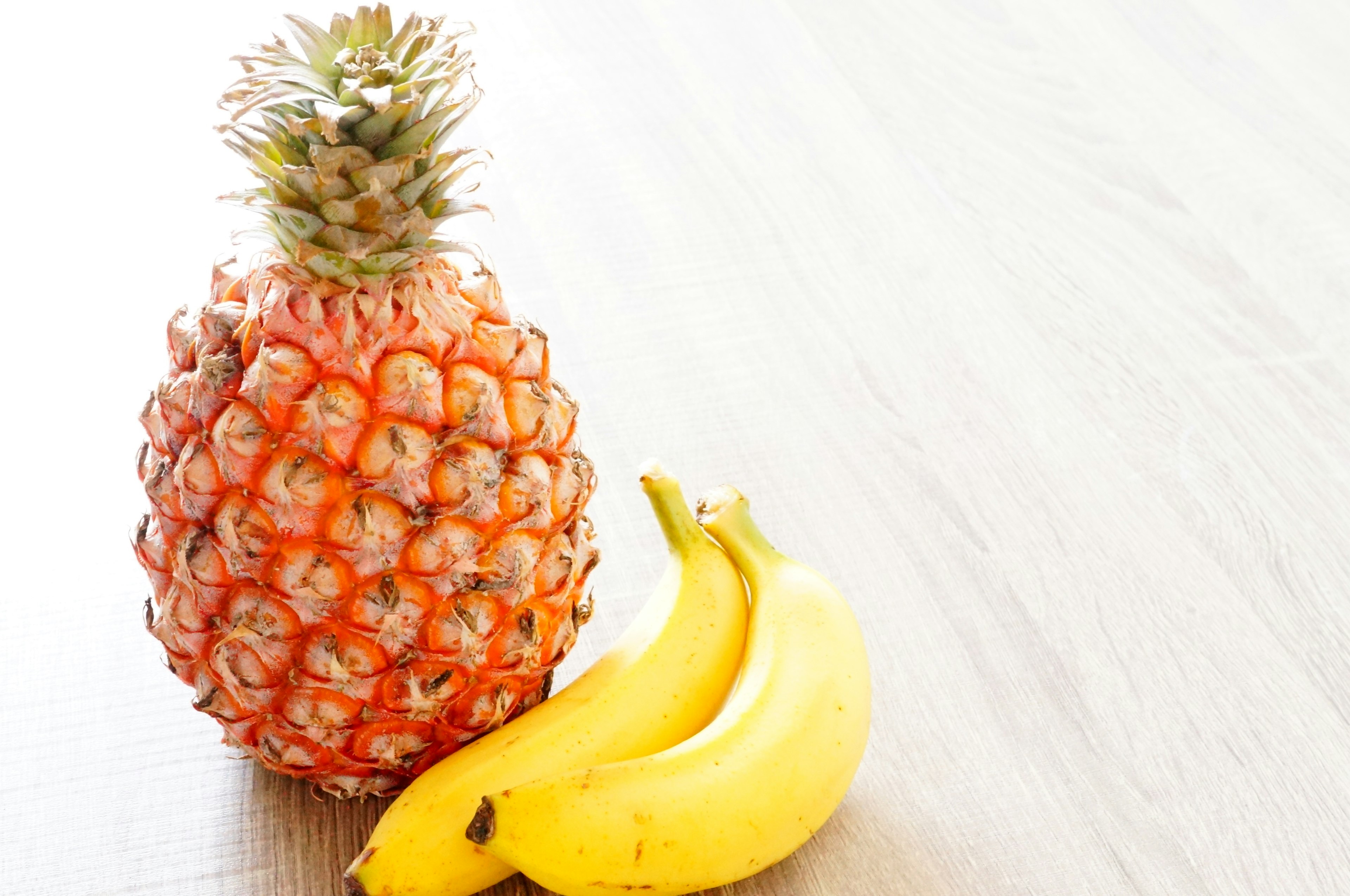 Un ananas et des bananes posés sur une table en bois