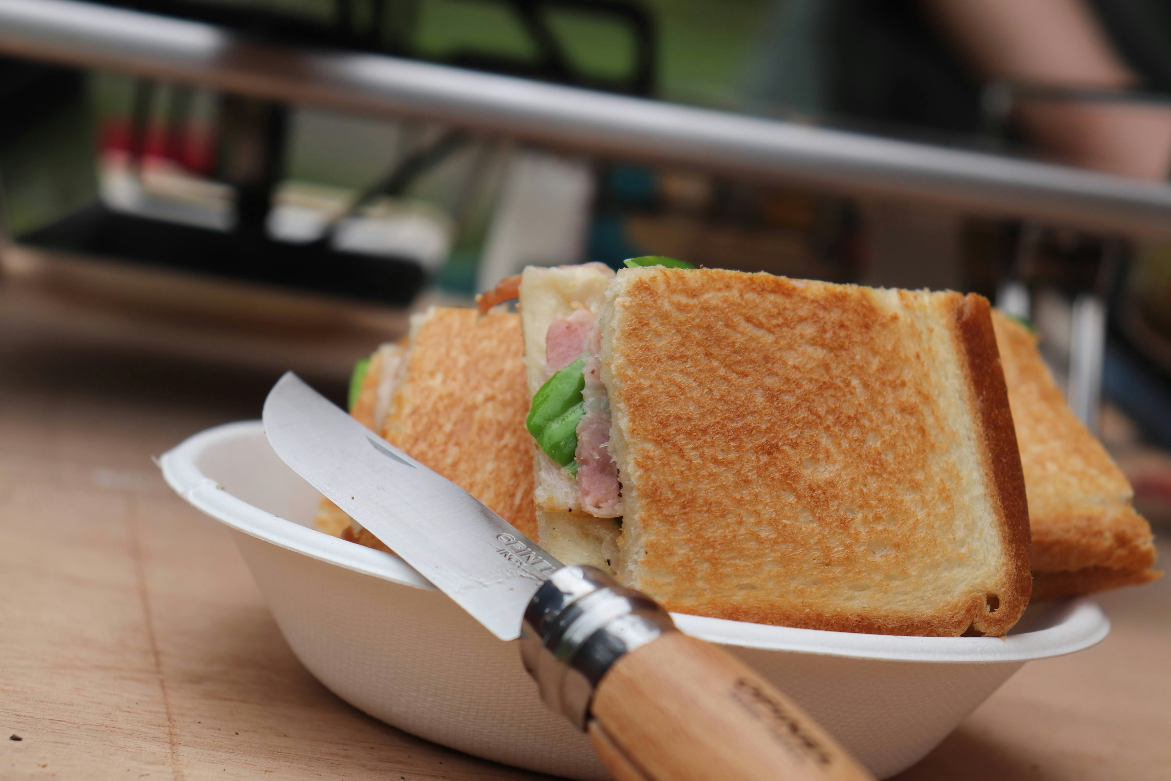 A sandwich placed in a bowl with toasted bread and a knife beside it