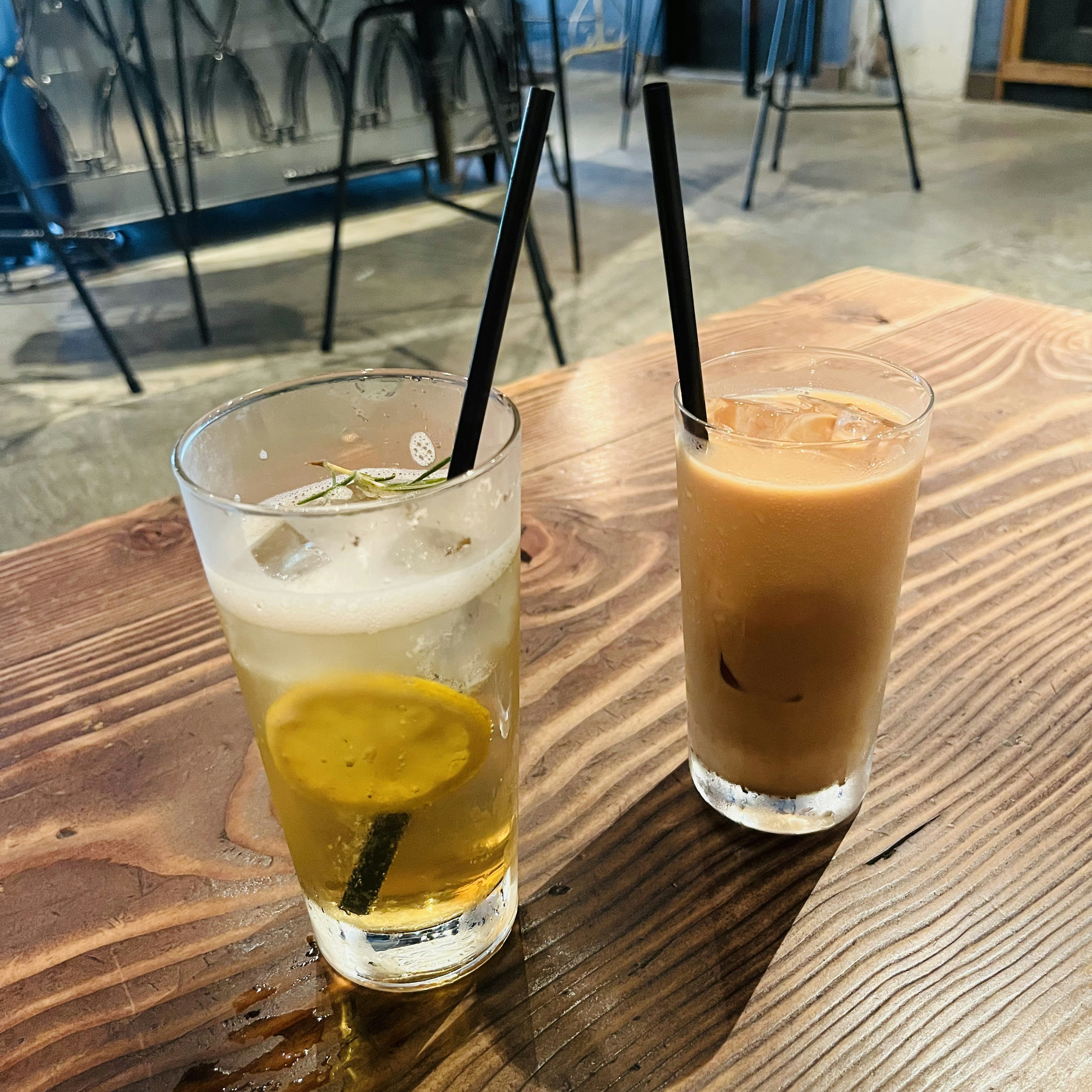 Deux boissons sur une table en bois. À gauche, une limonade au citron et à droite, un thé au lait glacé