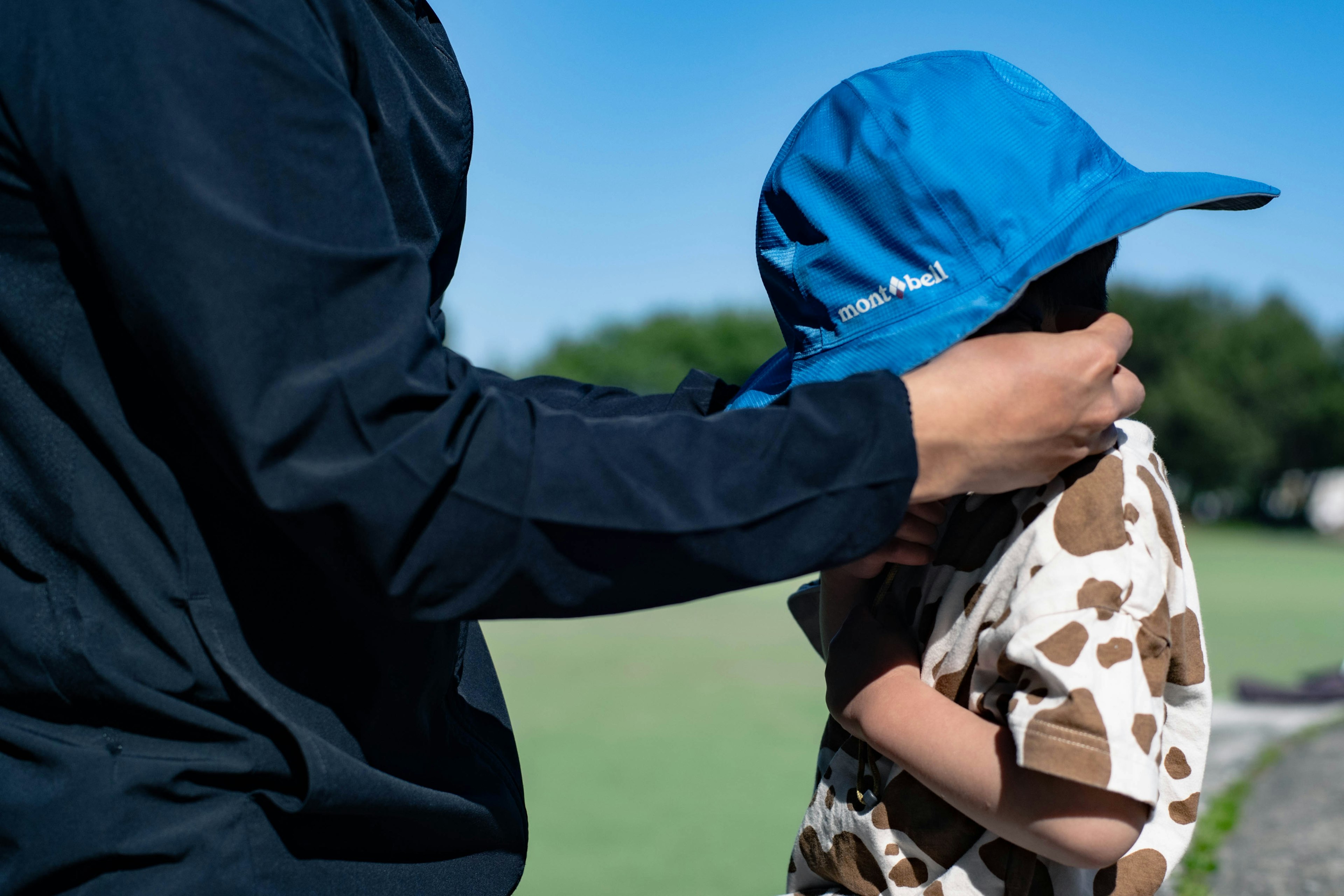 Child receiving a blue hat from an adult's hand