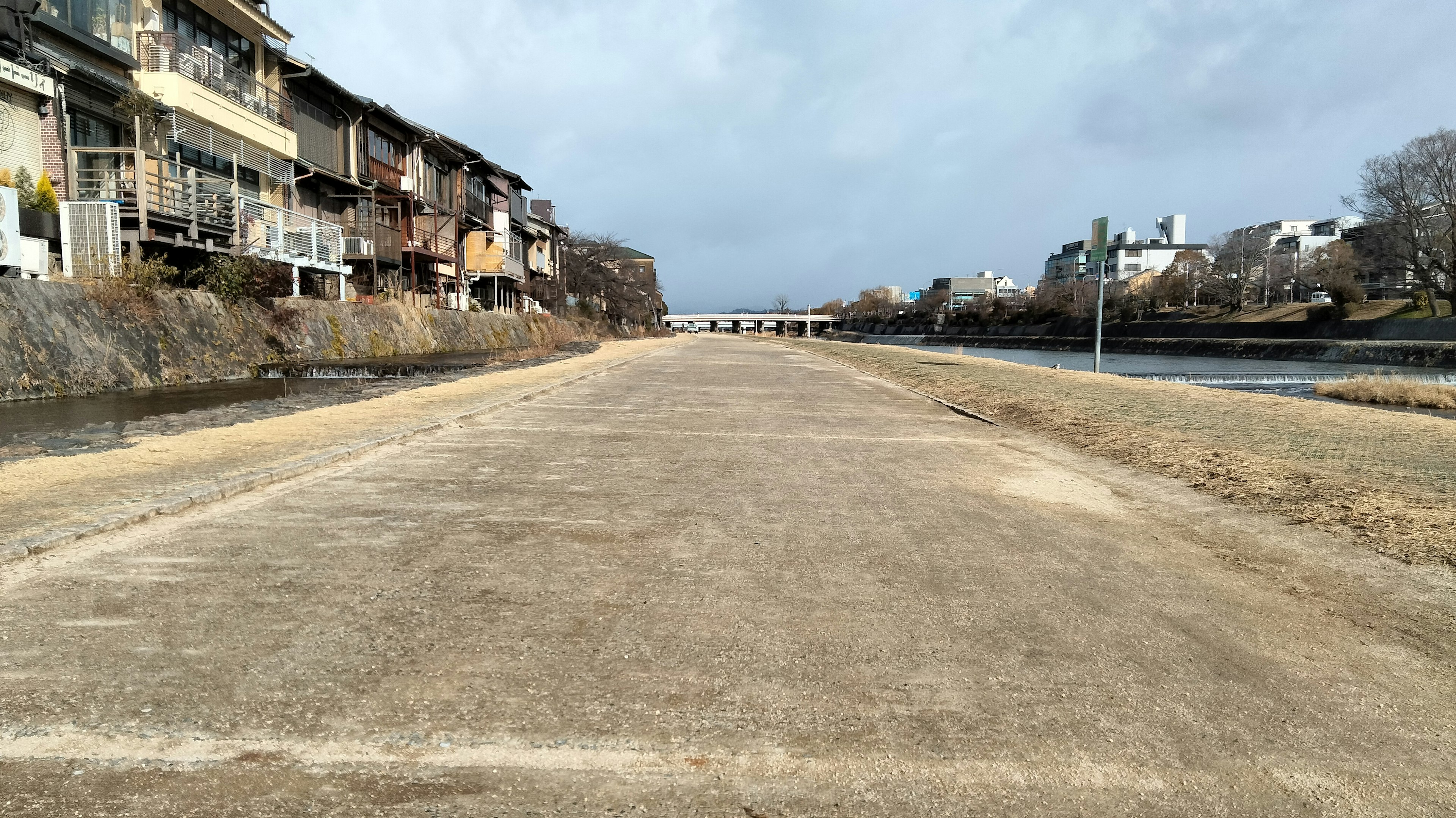 Pflasterweg entlang eines Flusses mit Gebäuden auf beiden Seiten