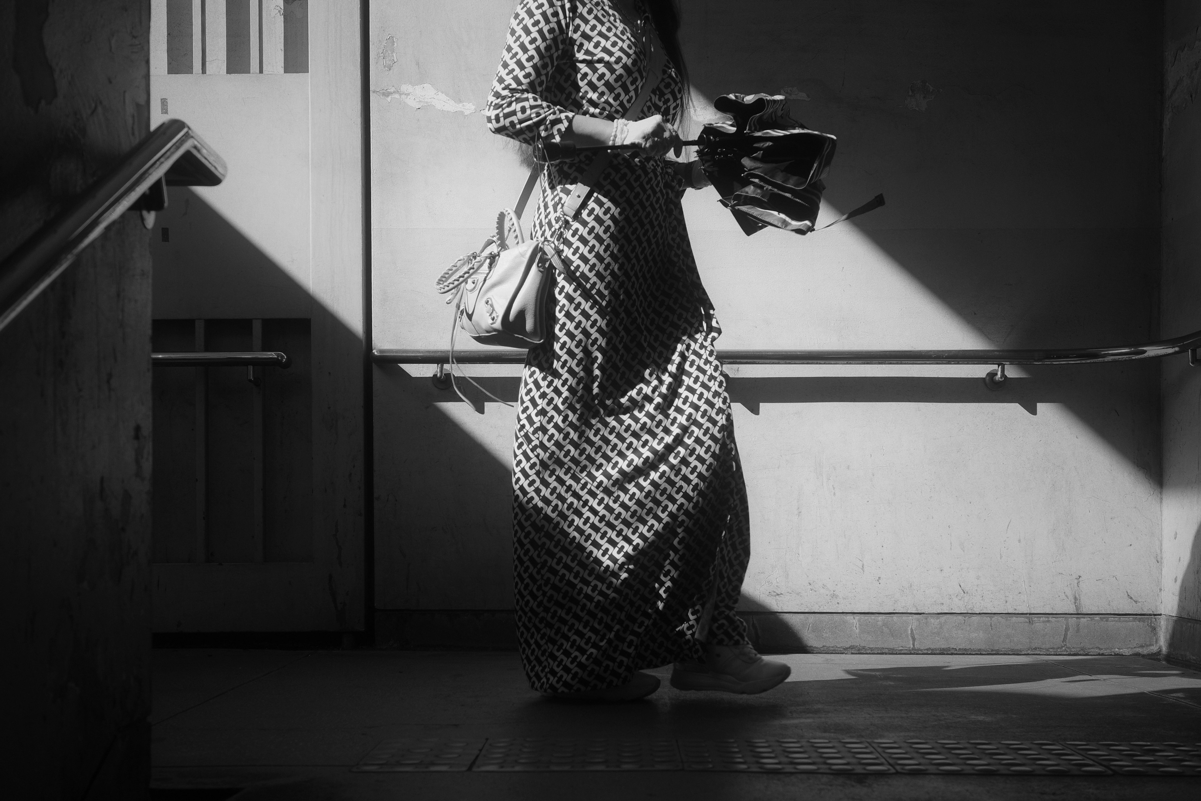 Foto en blanco y negro de una mujer con un vestido a cuadros caminando