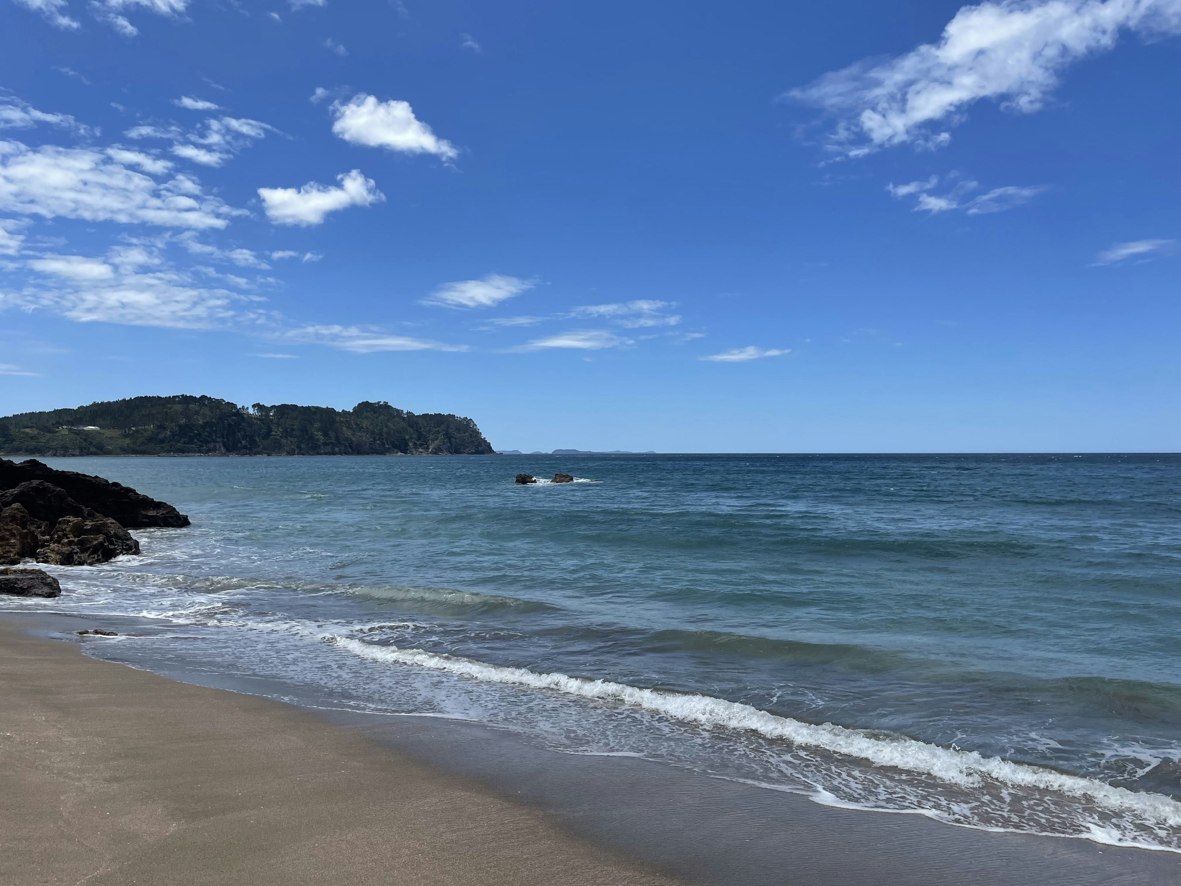 Malersicher Blick auf einen Strand mit blauem Meer und weißen Wellen