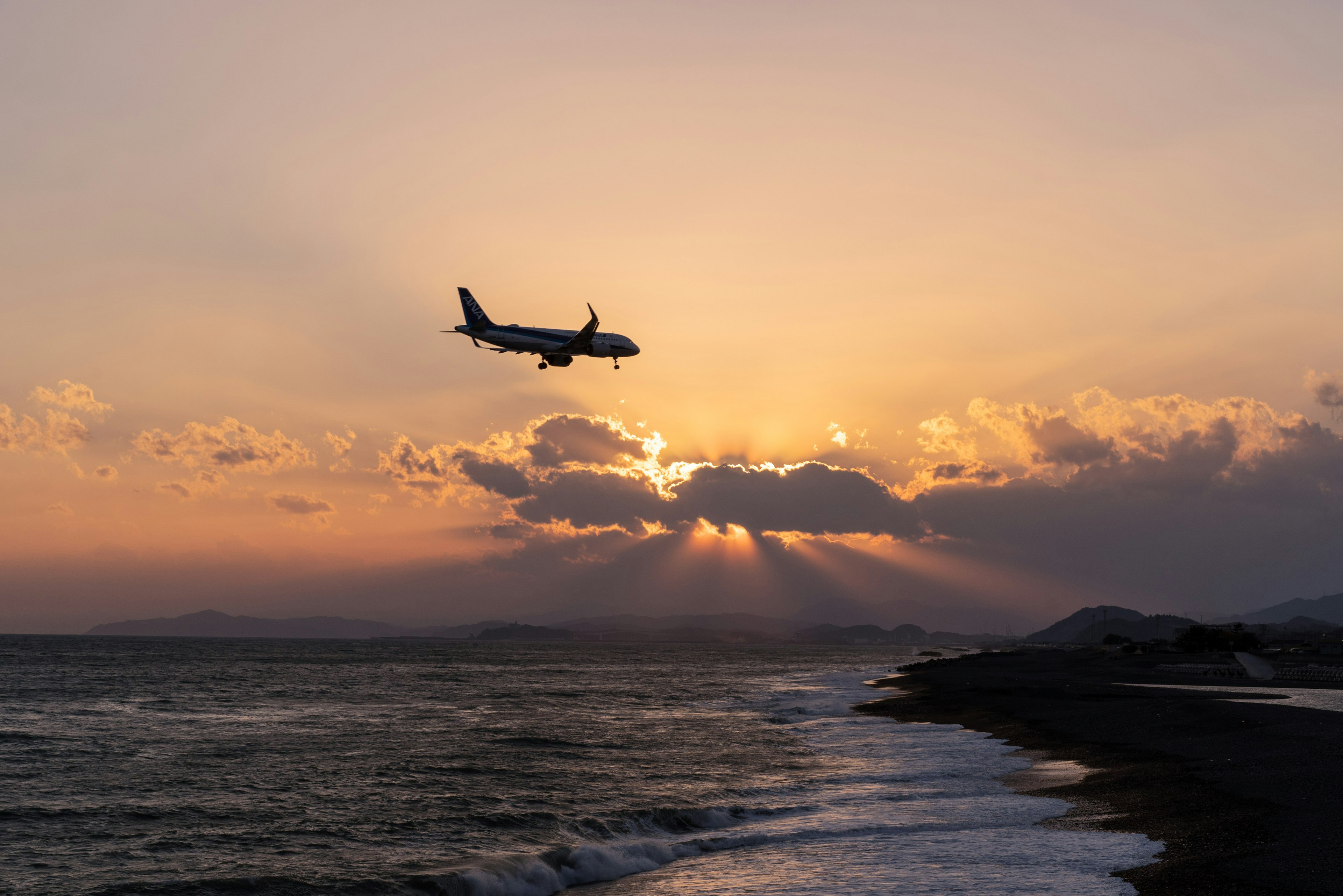 An airplane flying over a picturesque coastline during sunset