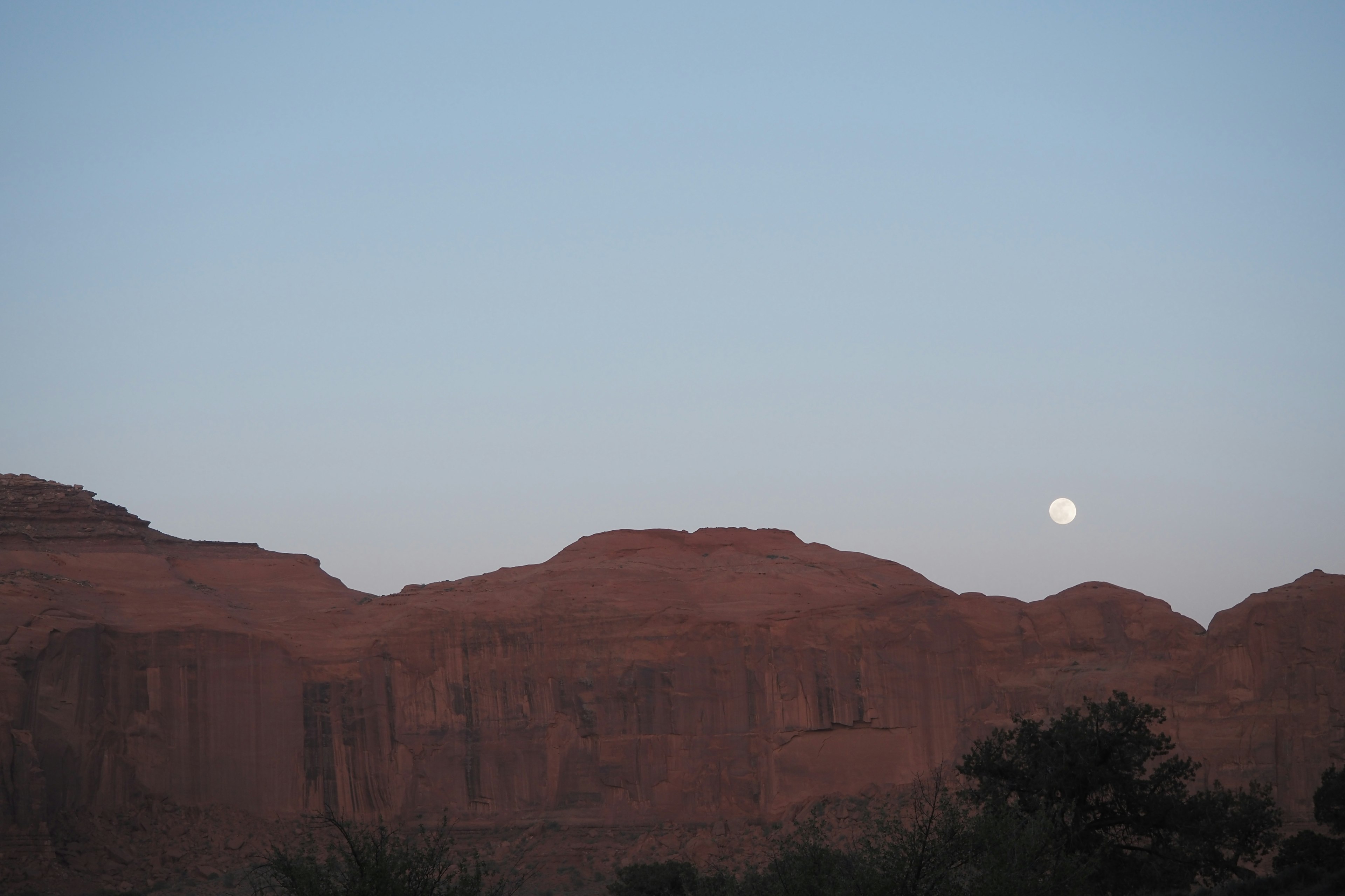 Rote Felsen unter einem Dämmerungshimmel mit einem aufgehenden Mond