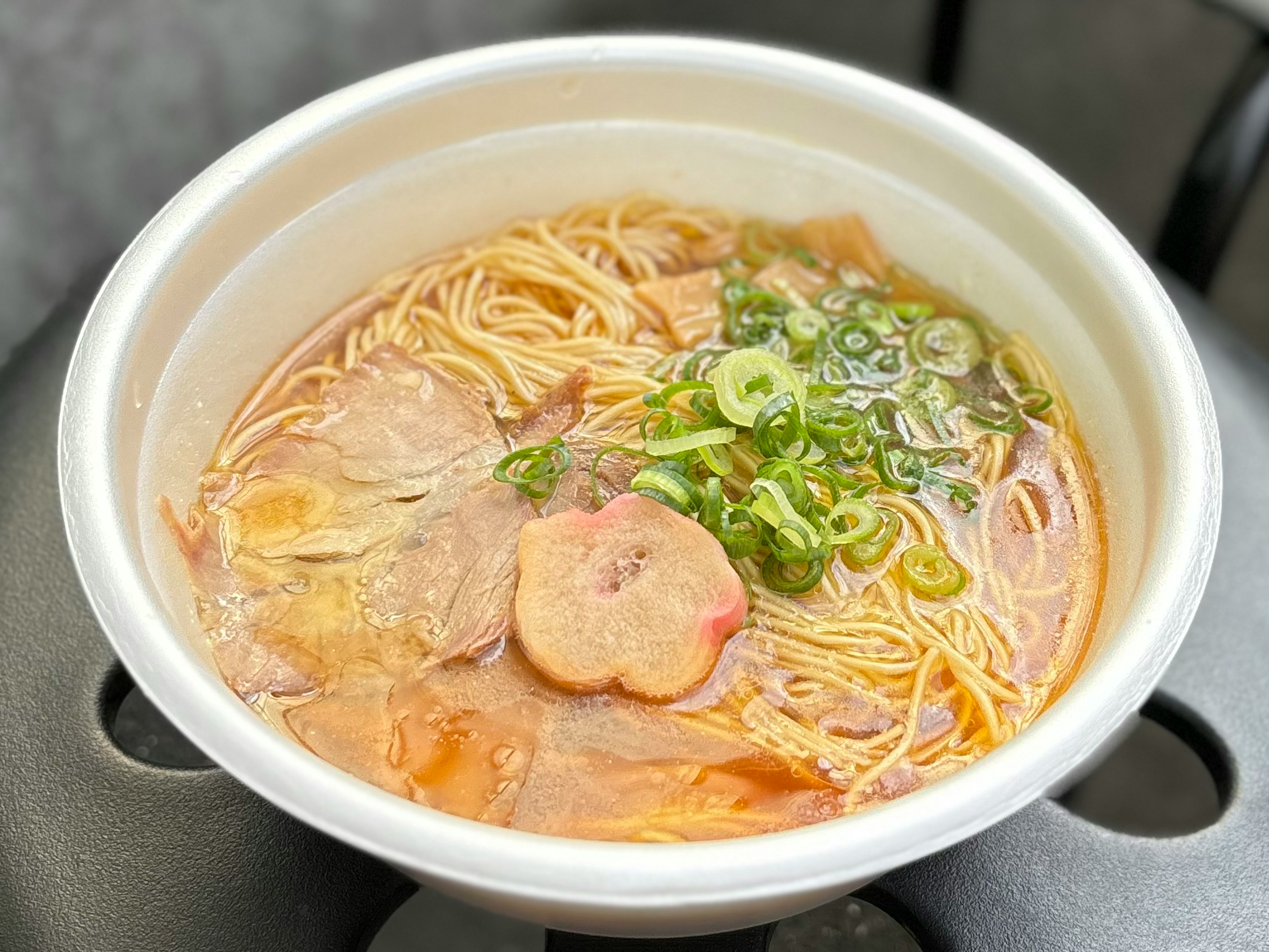 ラーメンのスープに細い麺とネギがトッピングされた温かい料理