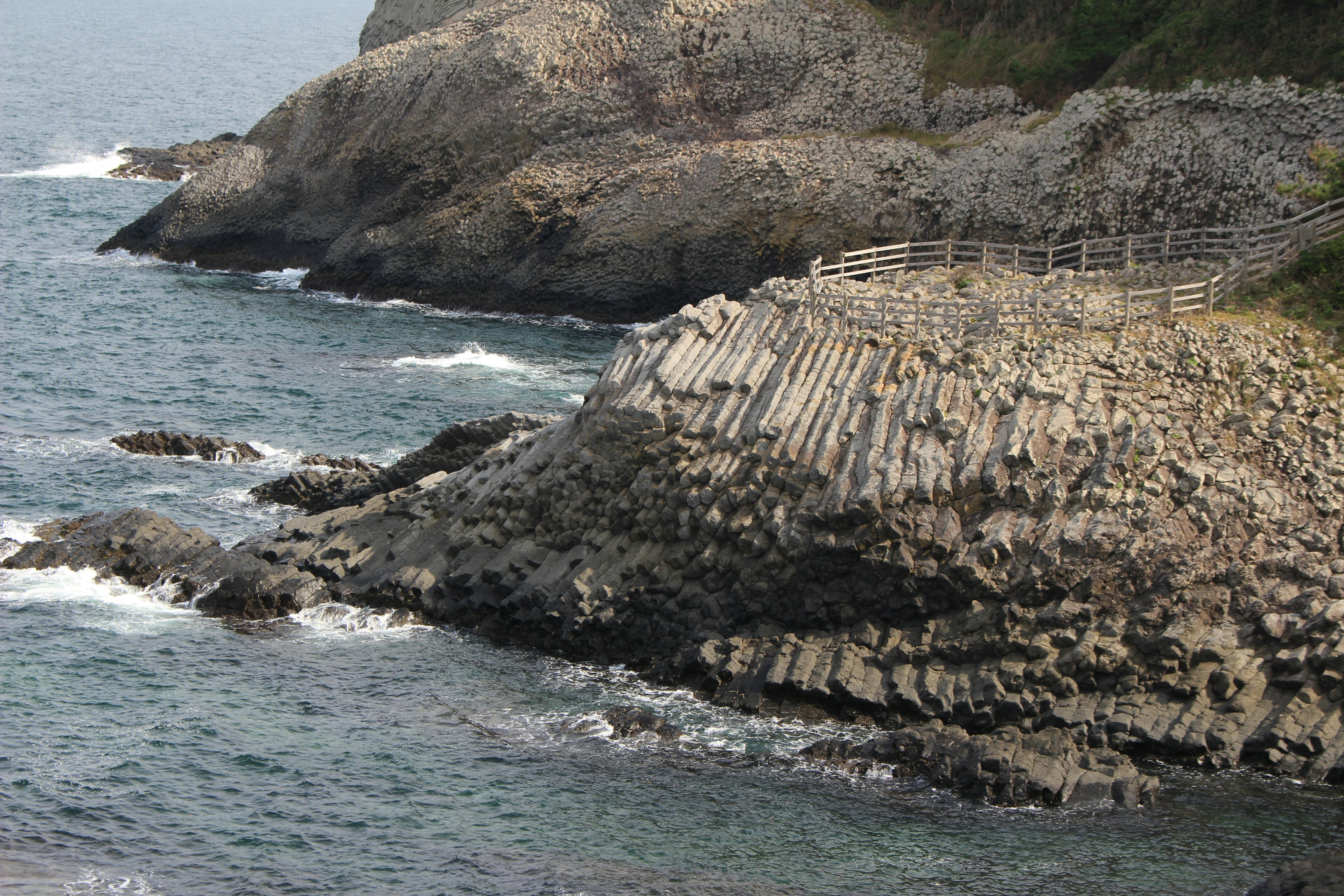 Coastal view featuring columnar basalt formations and crashing waves