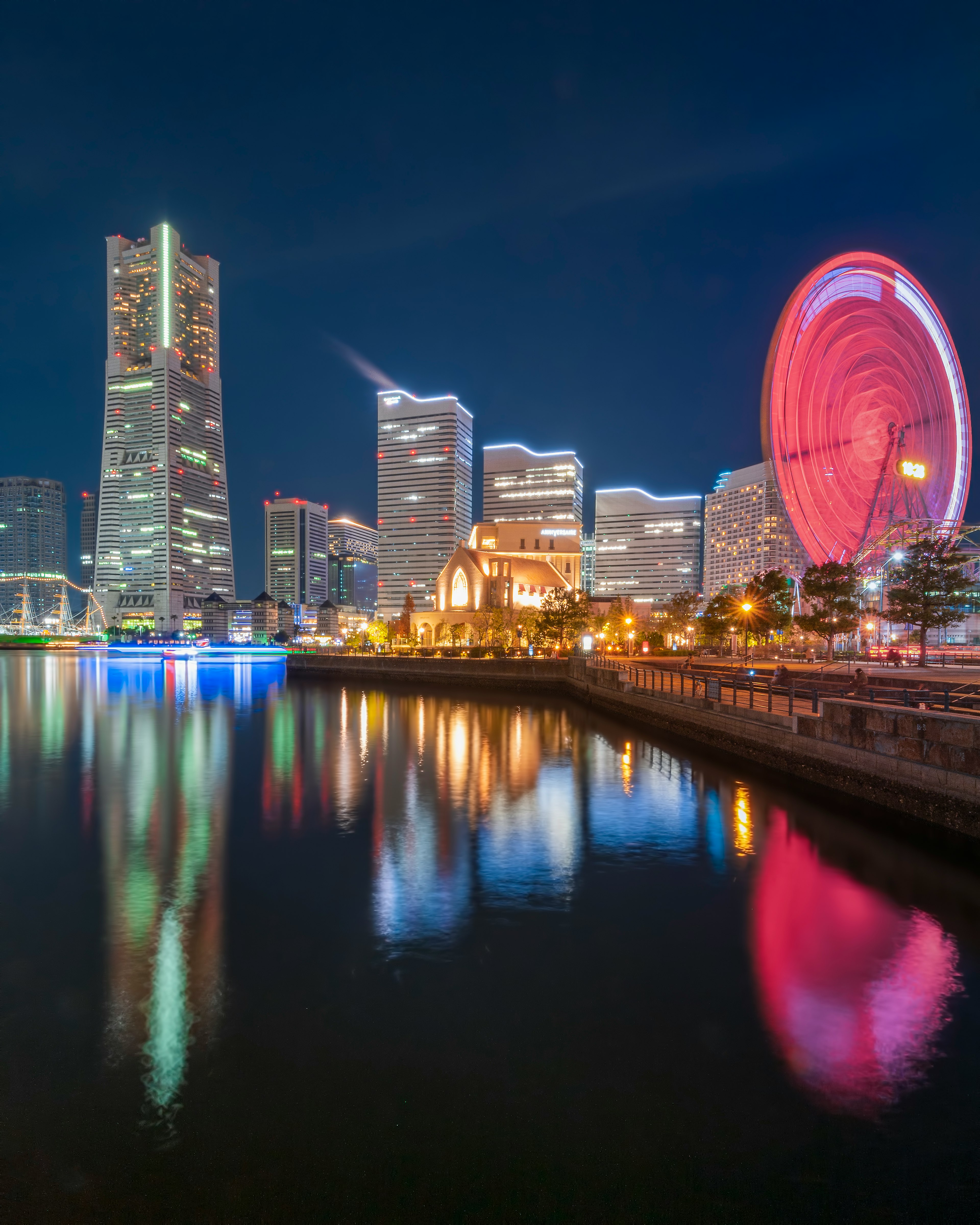 Nachtansicht von Yokohama mit Wolkenkratzern und einem Riesenrad, das sich im Wasser spiegelt