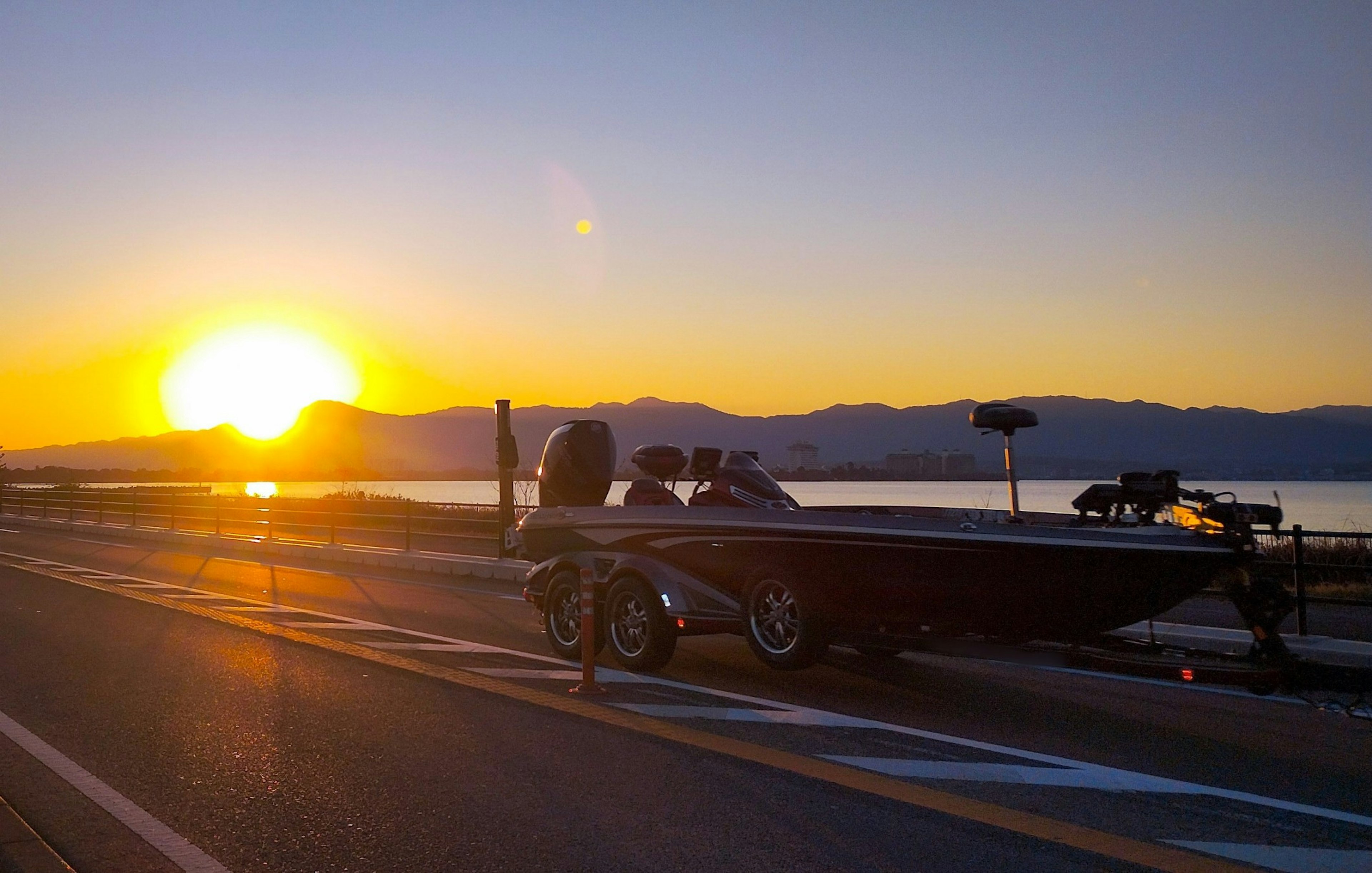 Barco en la carretera con atardecer y silueta de montaña