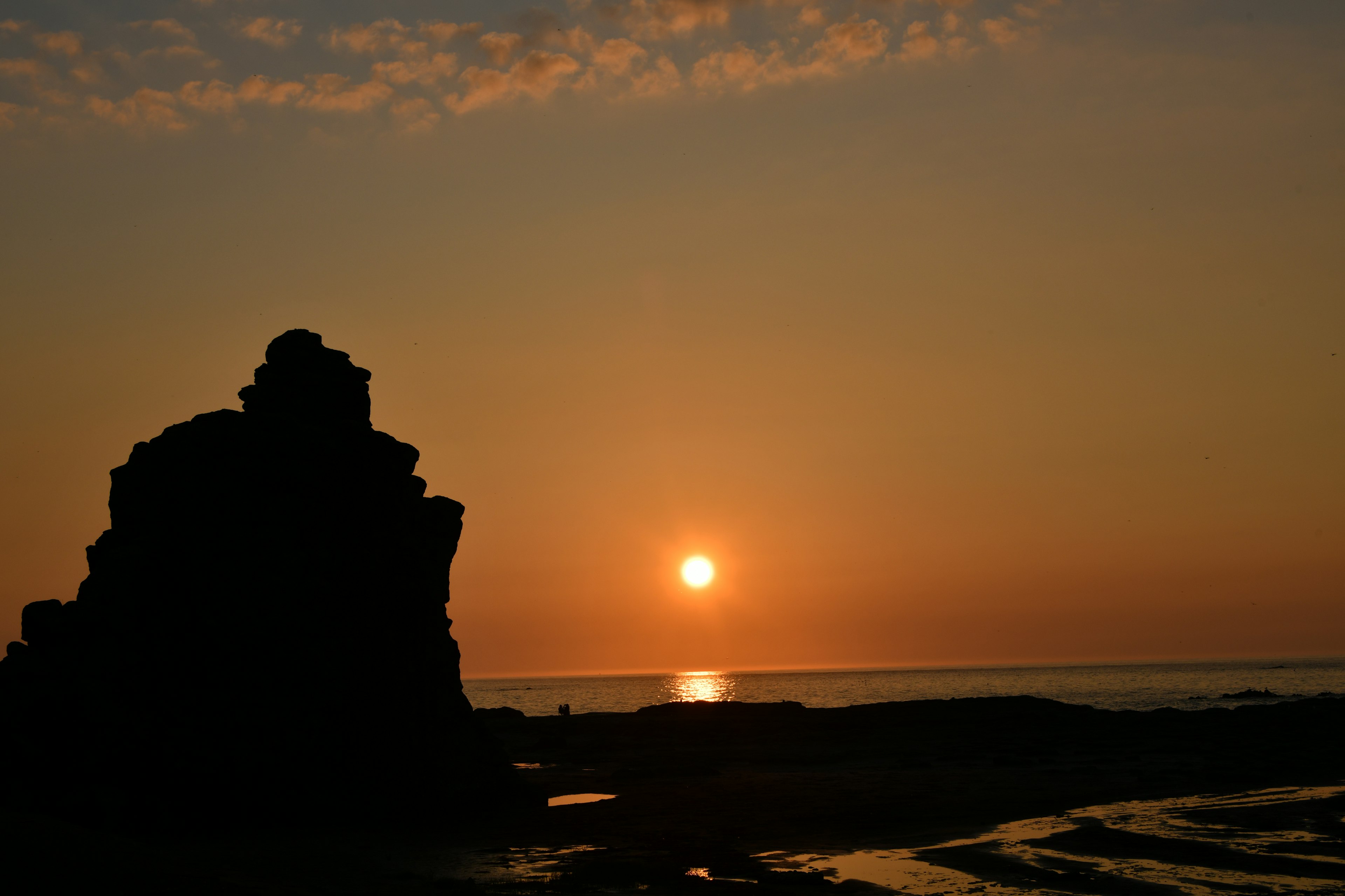 Silhouette of a rock at sunset by the sea