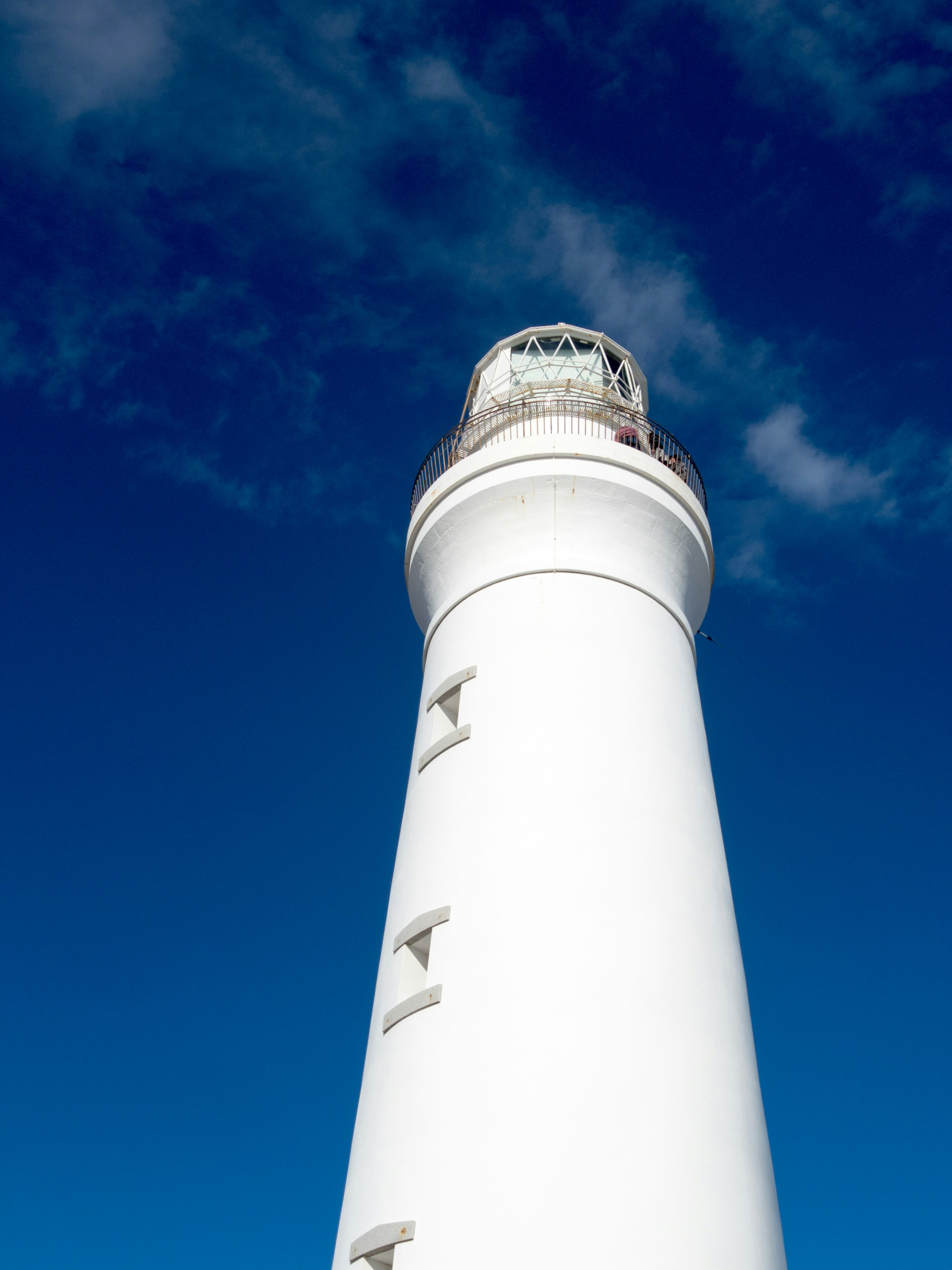 Close-up of a white lighthouse against a blue sky