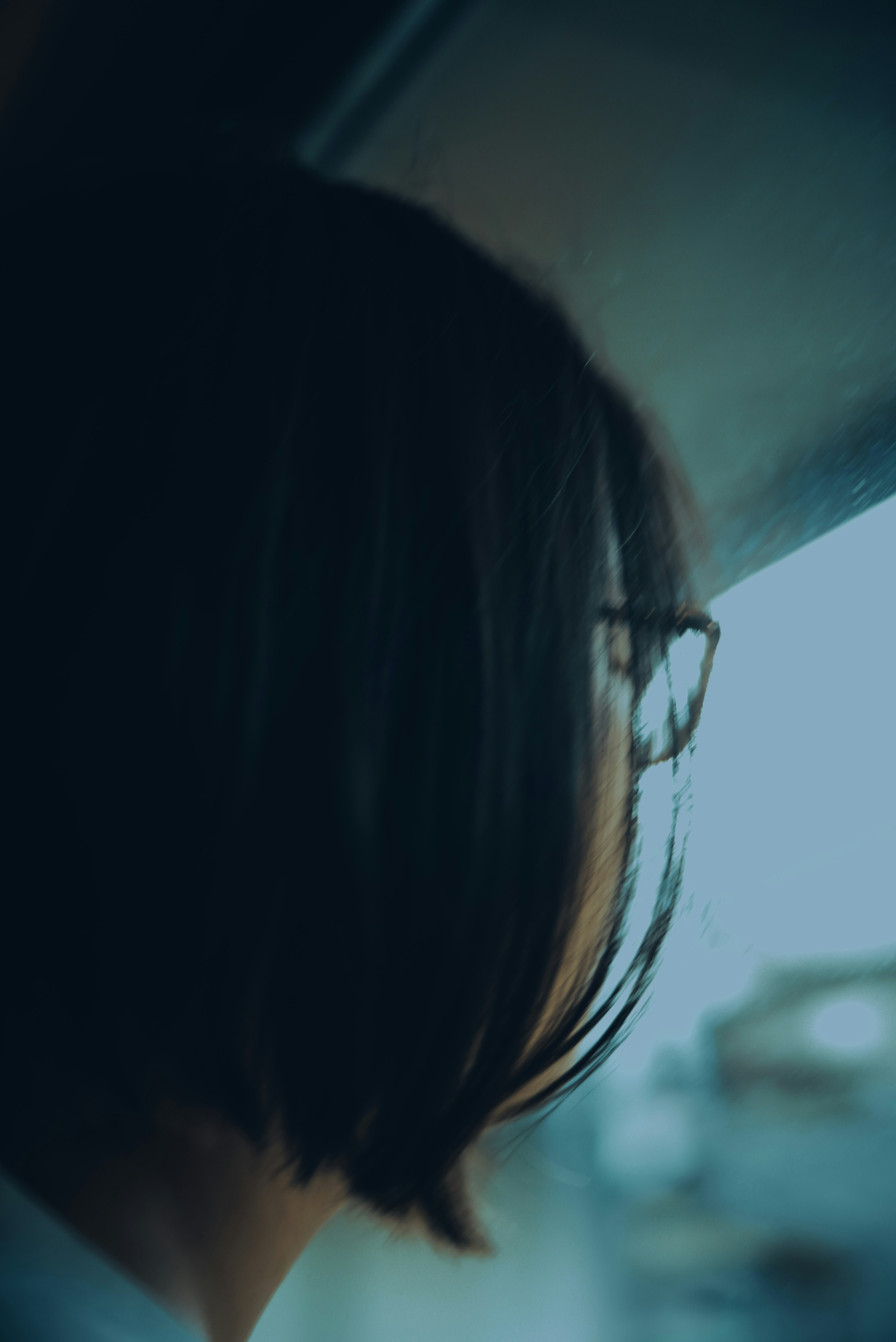 Rückansicht einer Frau mit Brille, die aus dem Fenster schaut