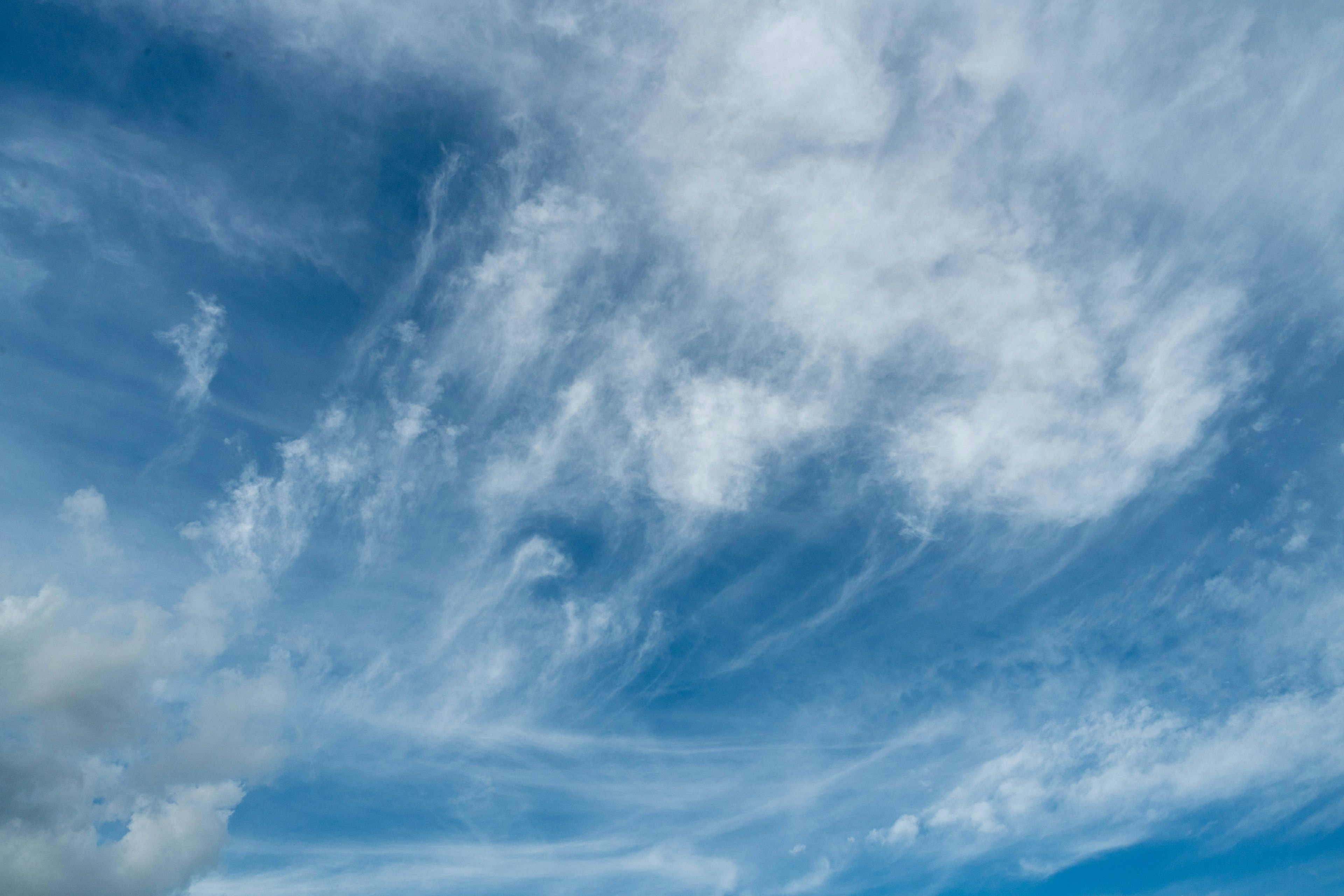 Weitläufiger blauer Himmel mit wispy weißen Wolken