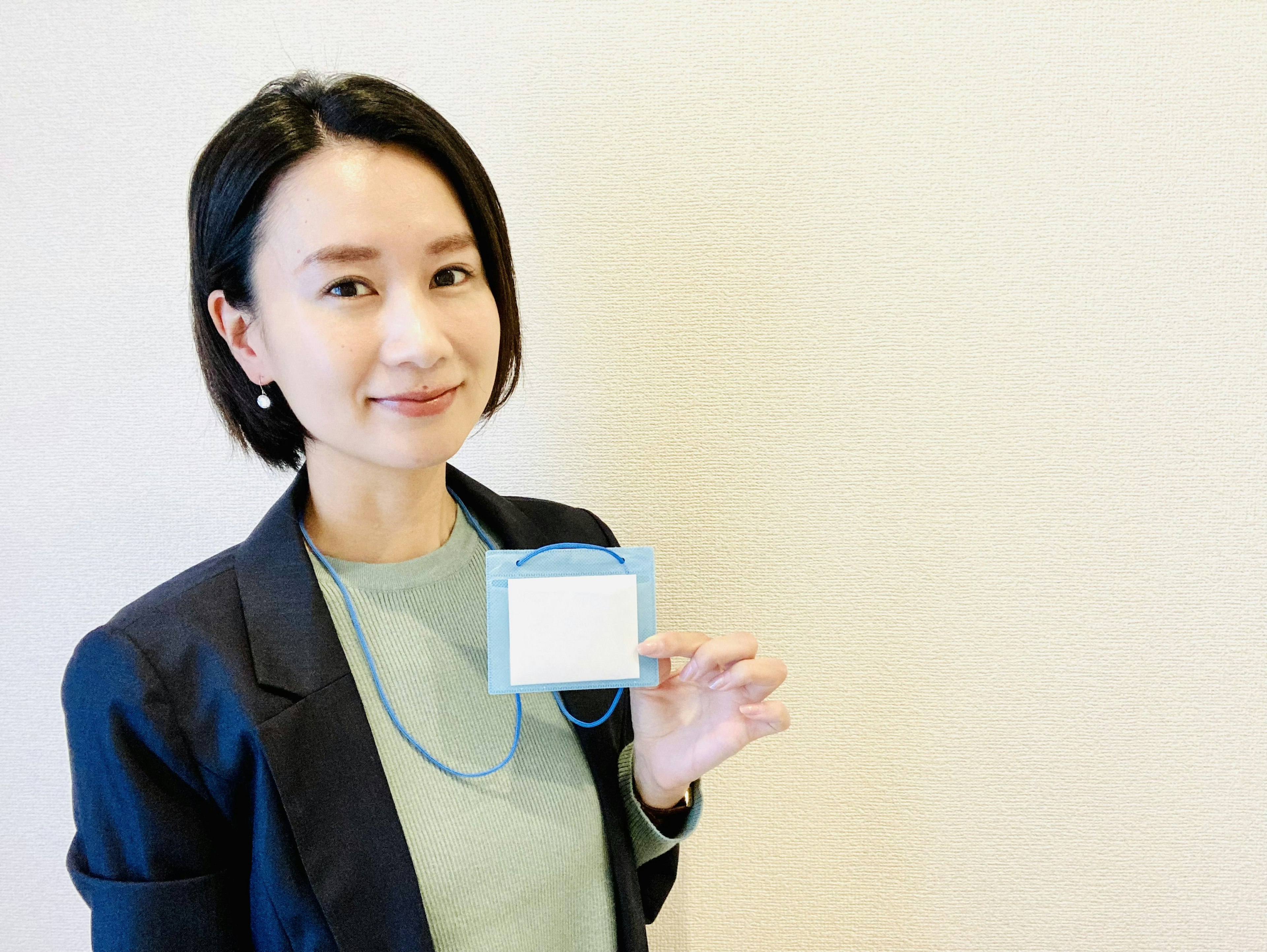 A woman smiling while holding a name tag