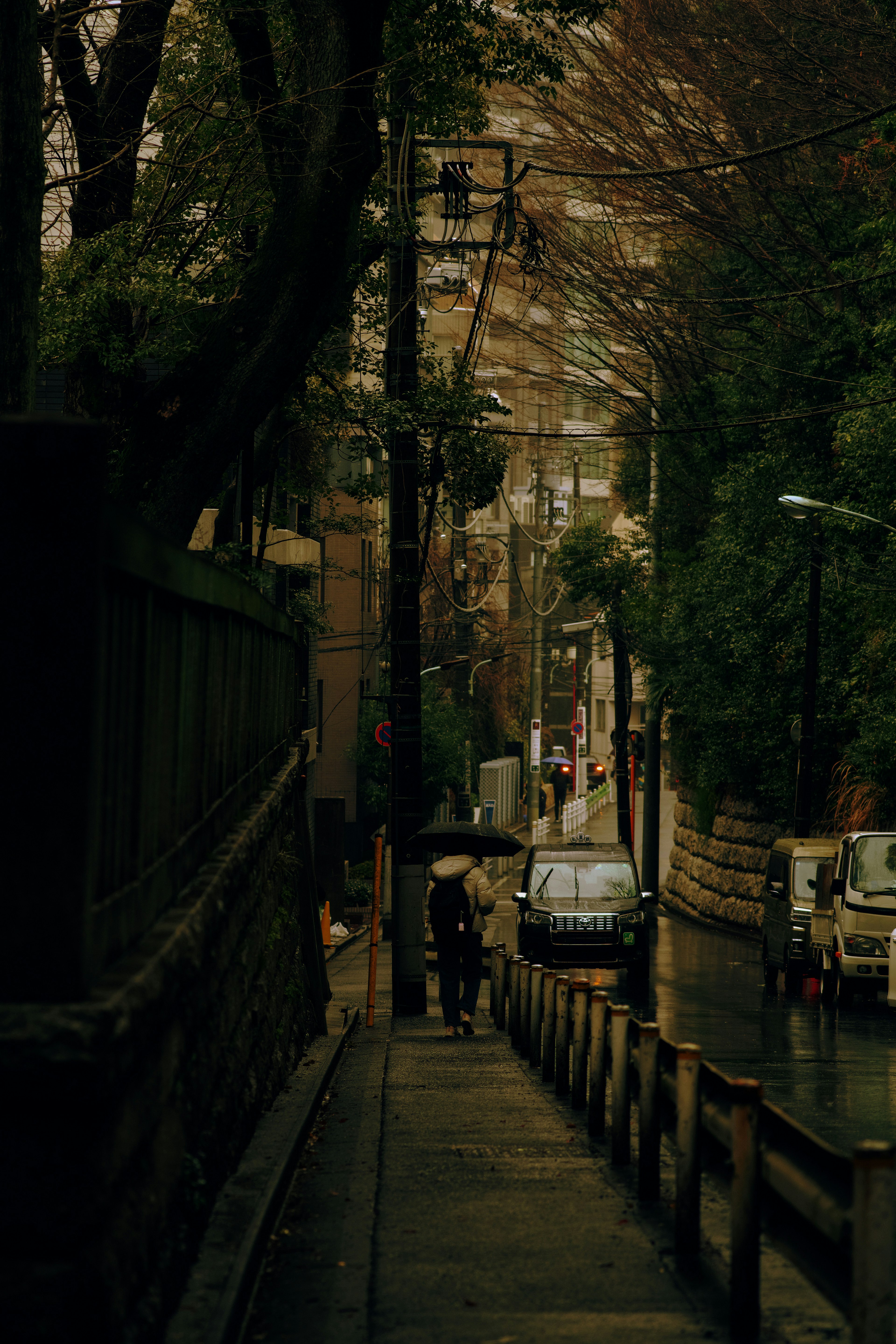 A street scene with people walking and cars visible in a dimly lit area