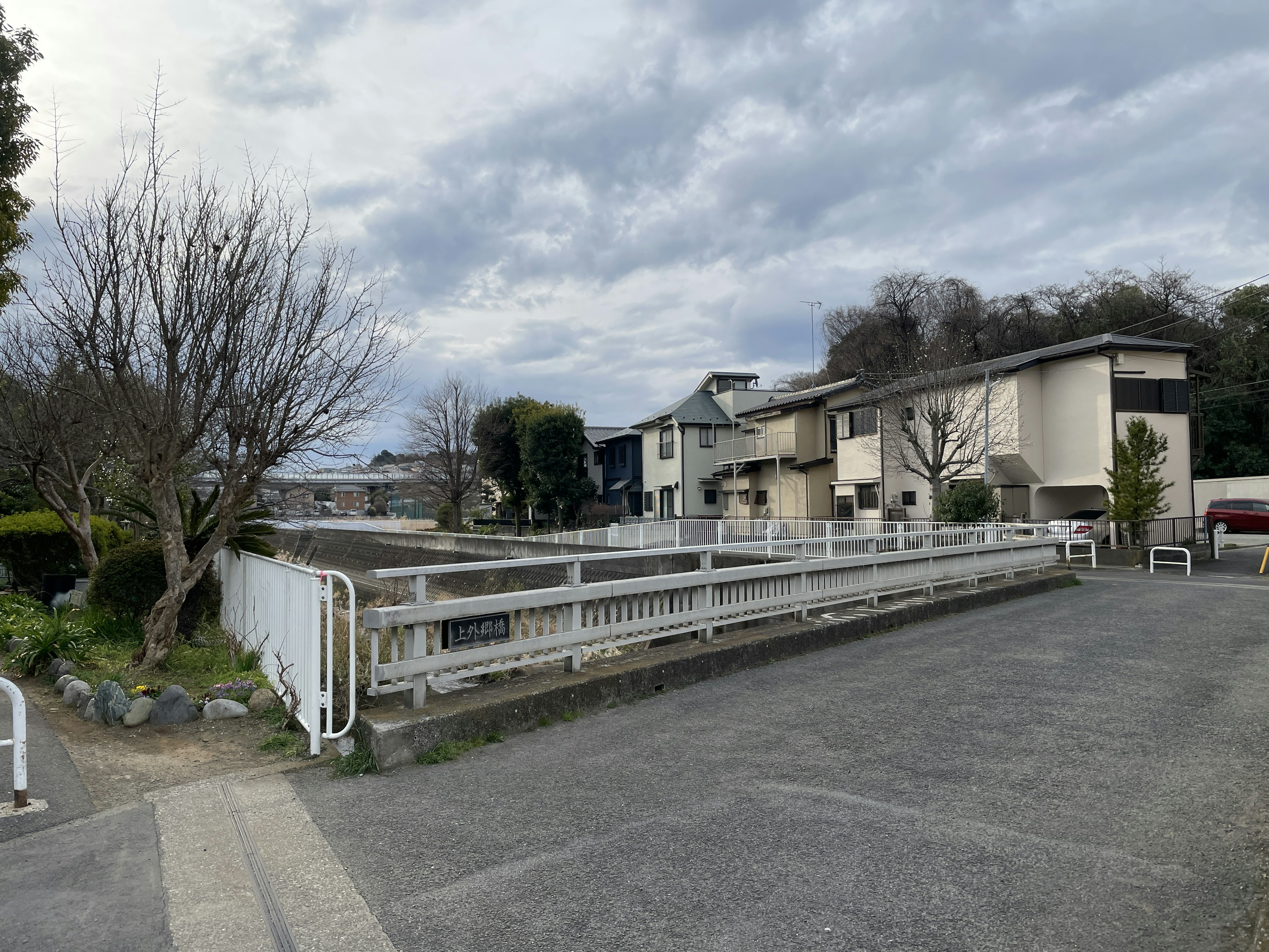 Quiet residential area landscape with gray sky and white fence featuring surrounding buildings