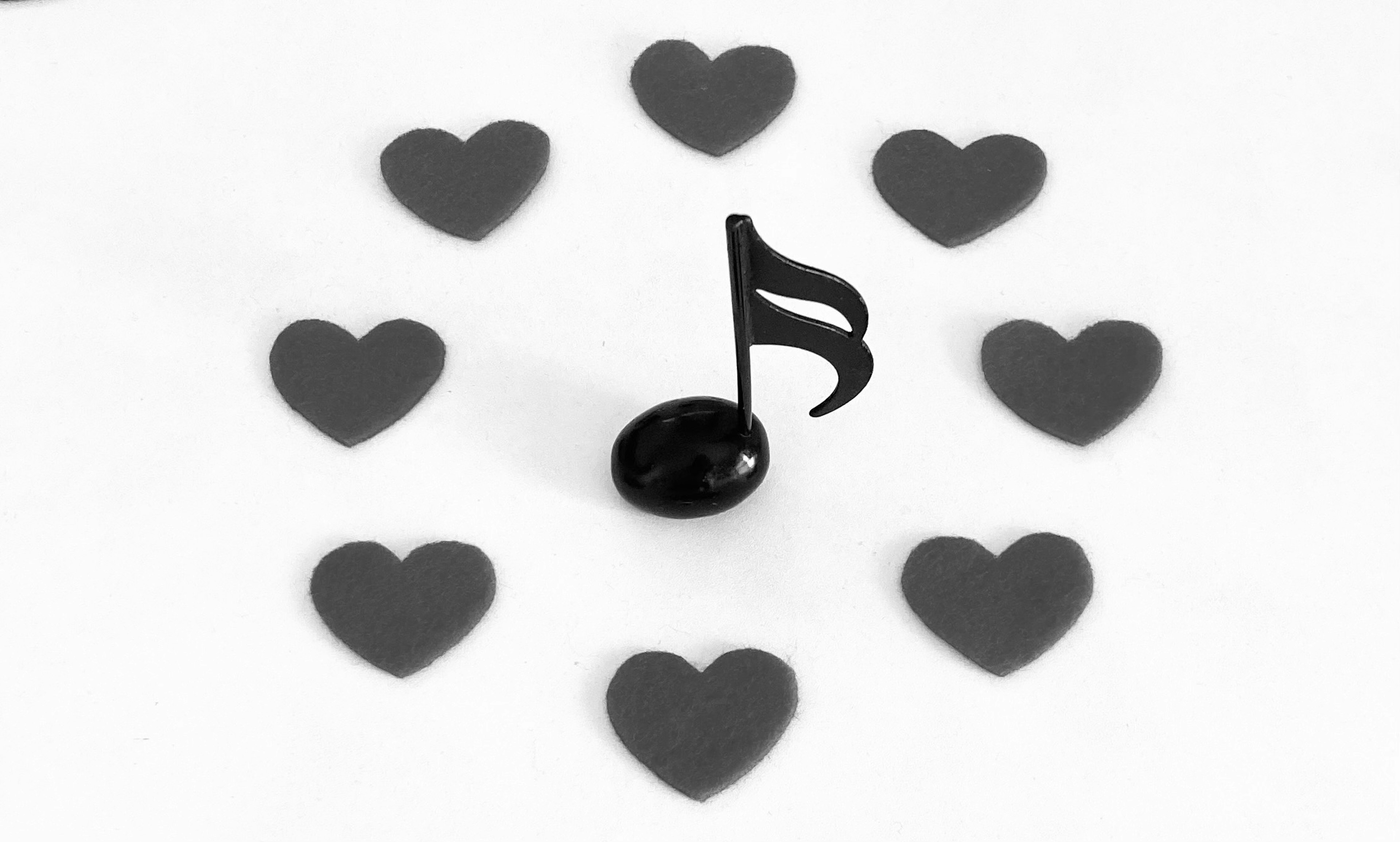 A black musical note surrounded by heart shapes in a circular arrangement