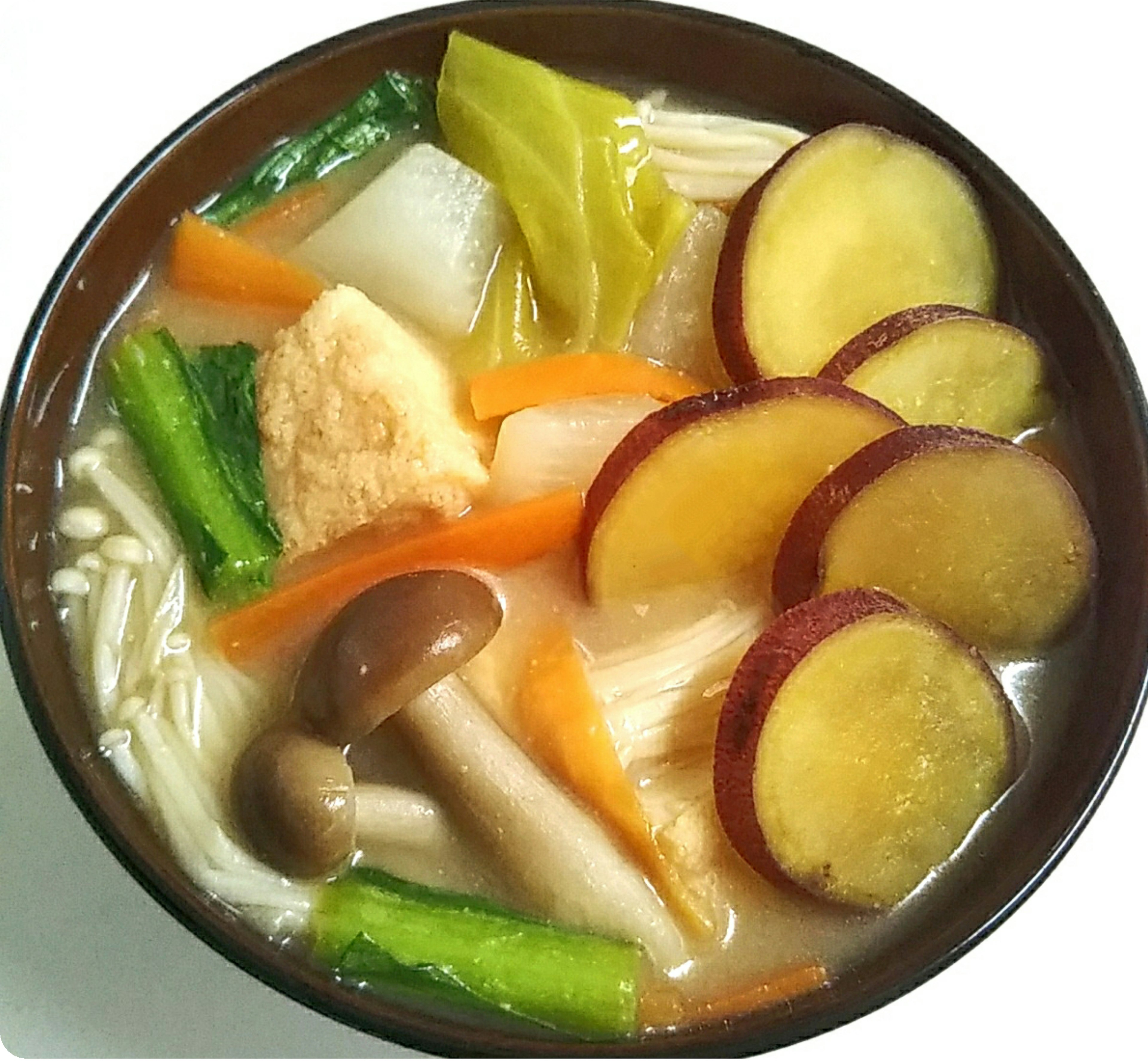 Bowl of warm vegetable soup featuring assorted vegetables including sweet potatoes and mushrooms