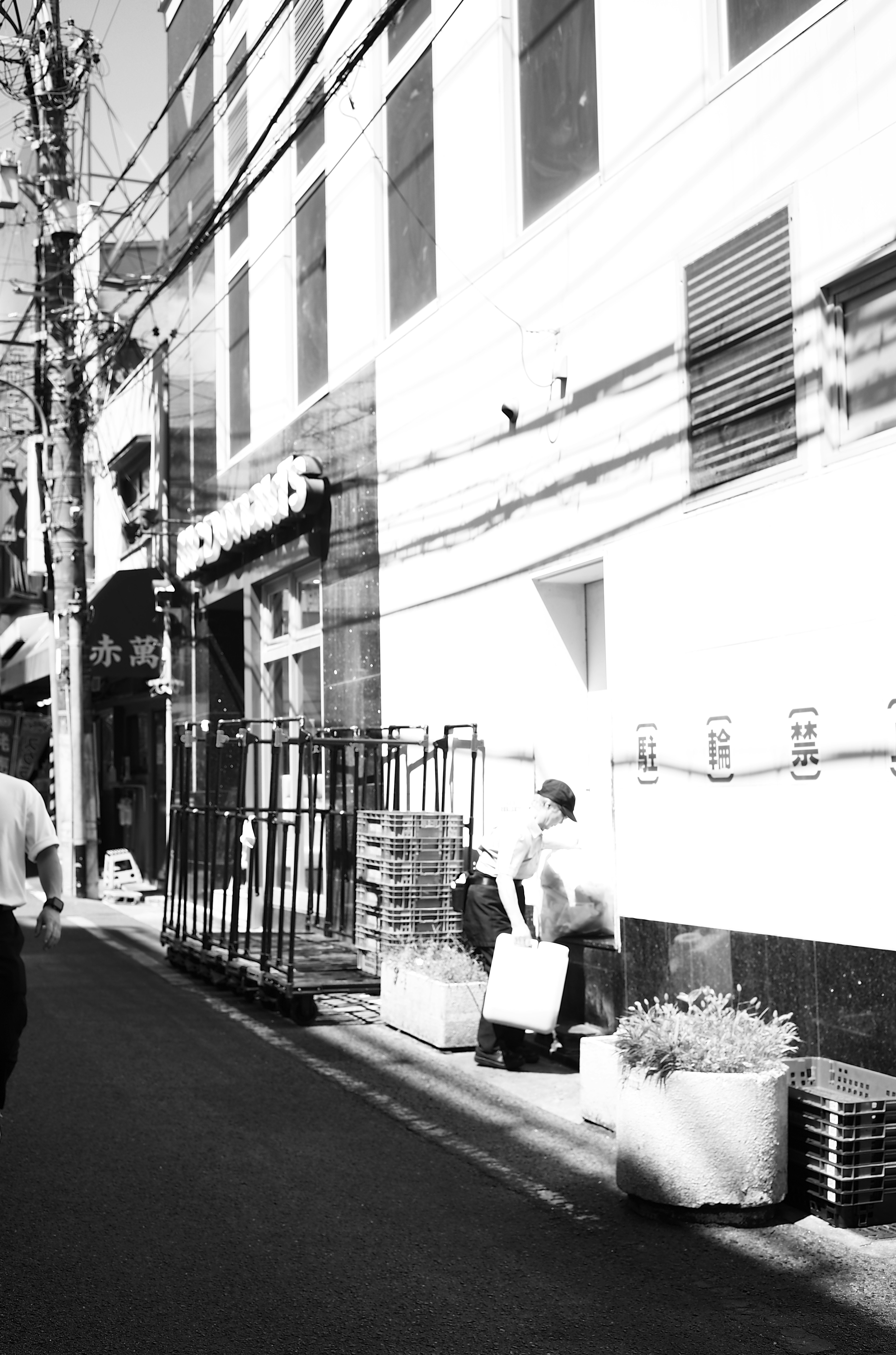 Black and white street scene featuring a man sitting and surrounding buildings