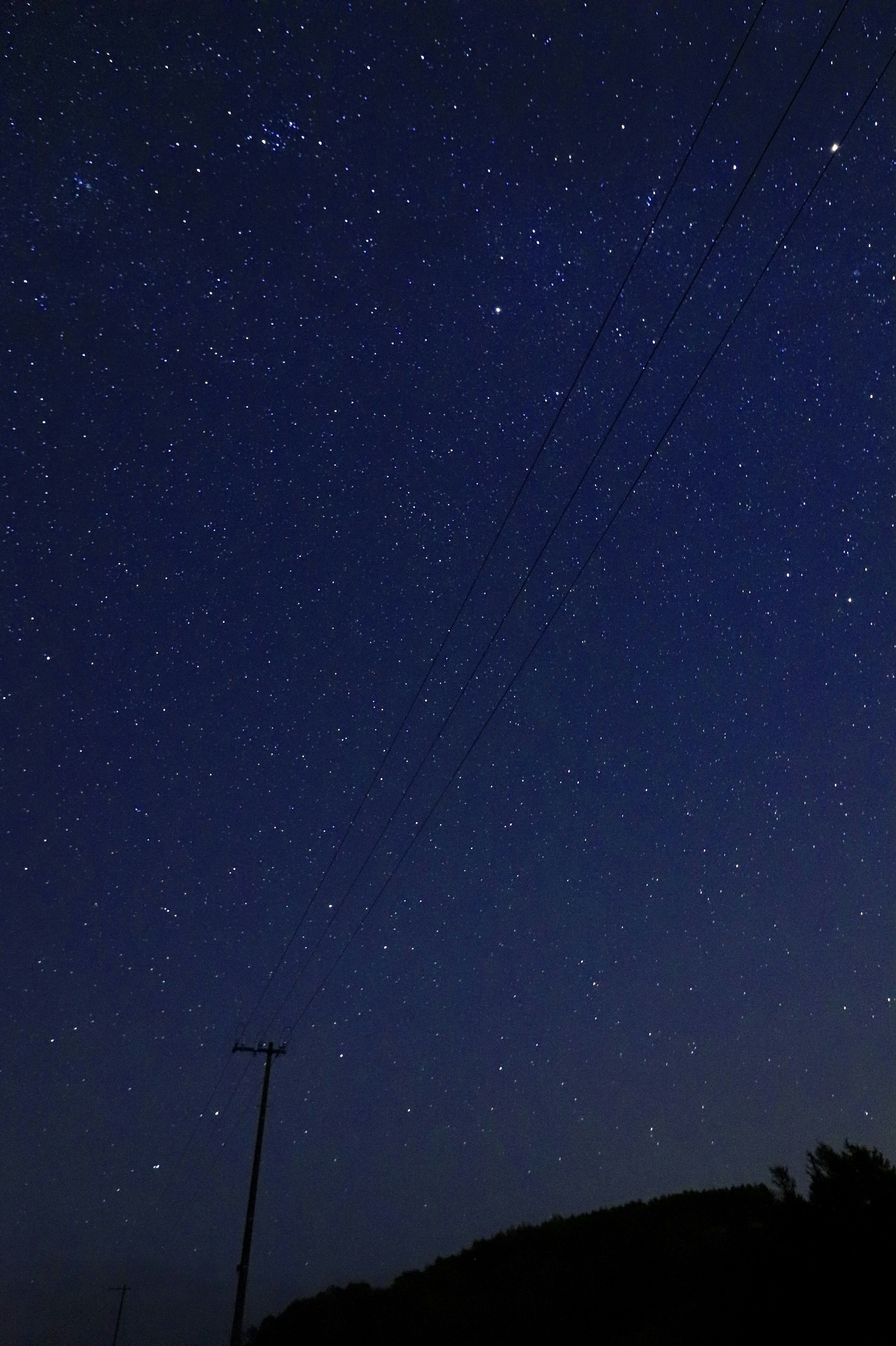 Cielo estrellado con estrellas brillantes y la silueta oscura de una colina