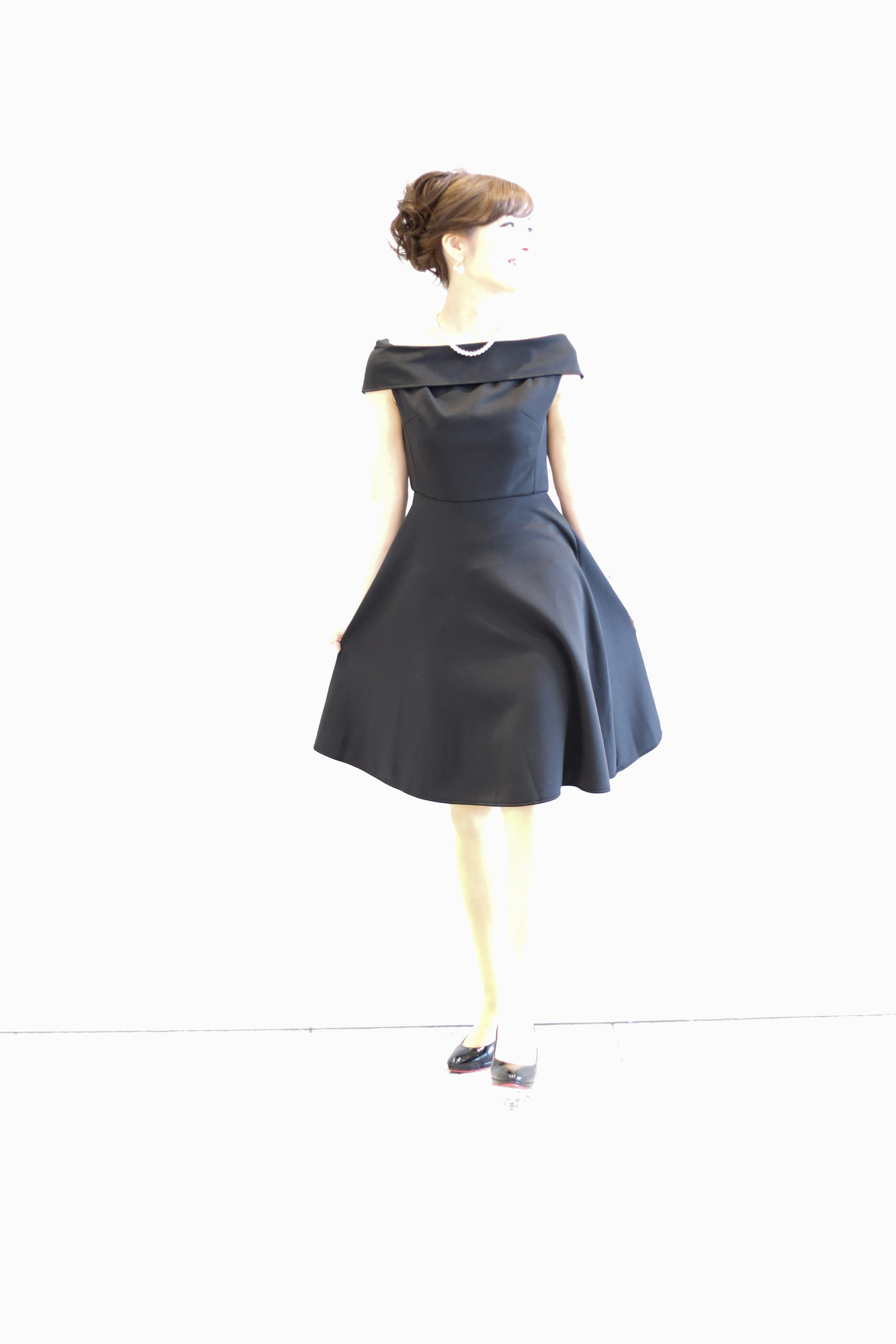 A mannequin wearing a black dress standing against a simple background