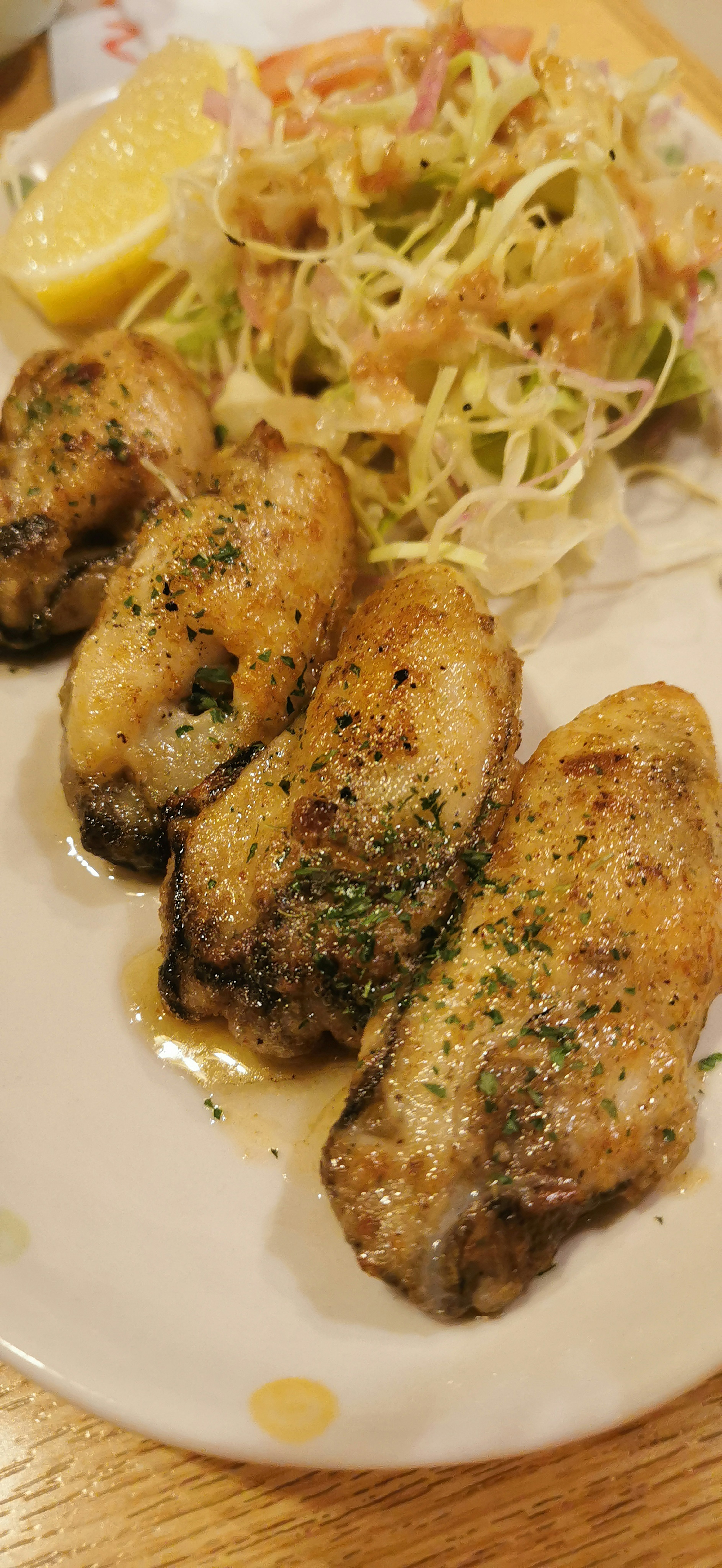 Teller mit gegrillten Hähnchenflügeln, Salat und Zitrone