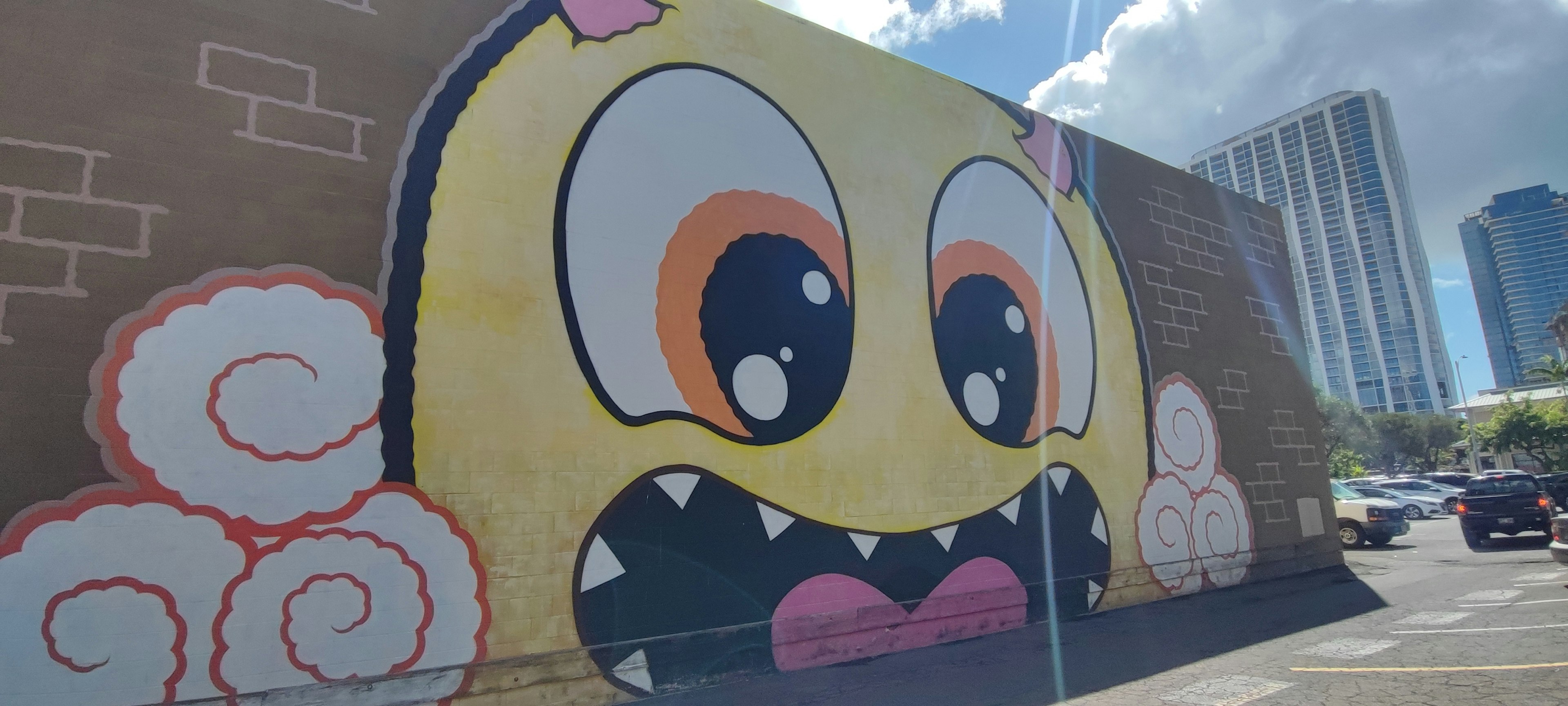 A large colorful monster face mural on a brick wall