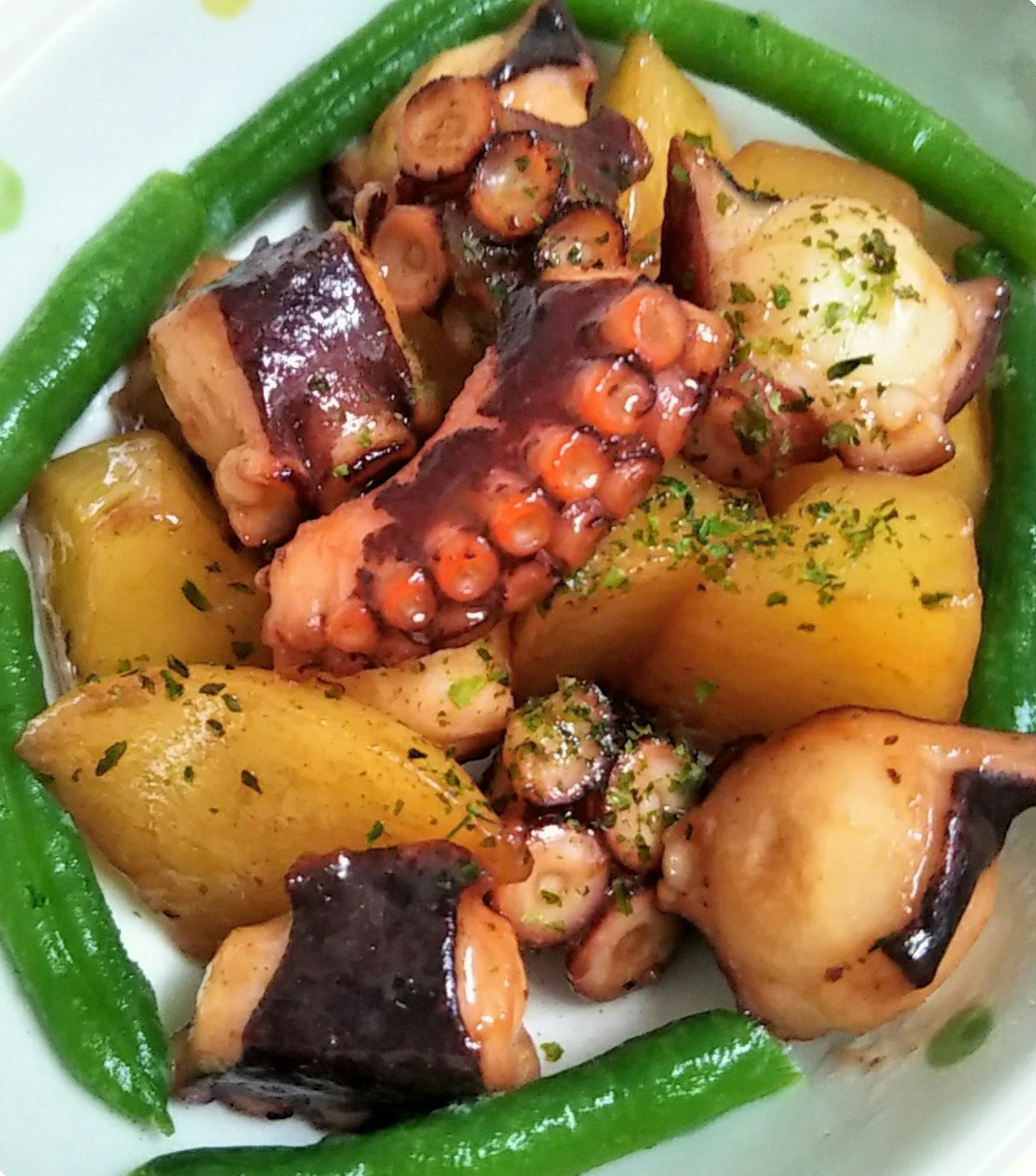 Dish featuring octopus and potatoes garnished with green beans