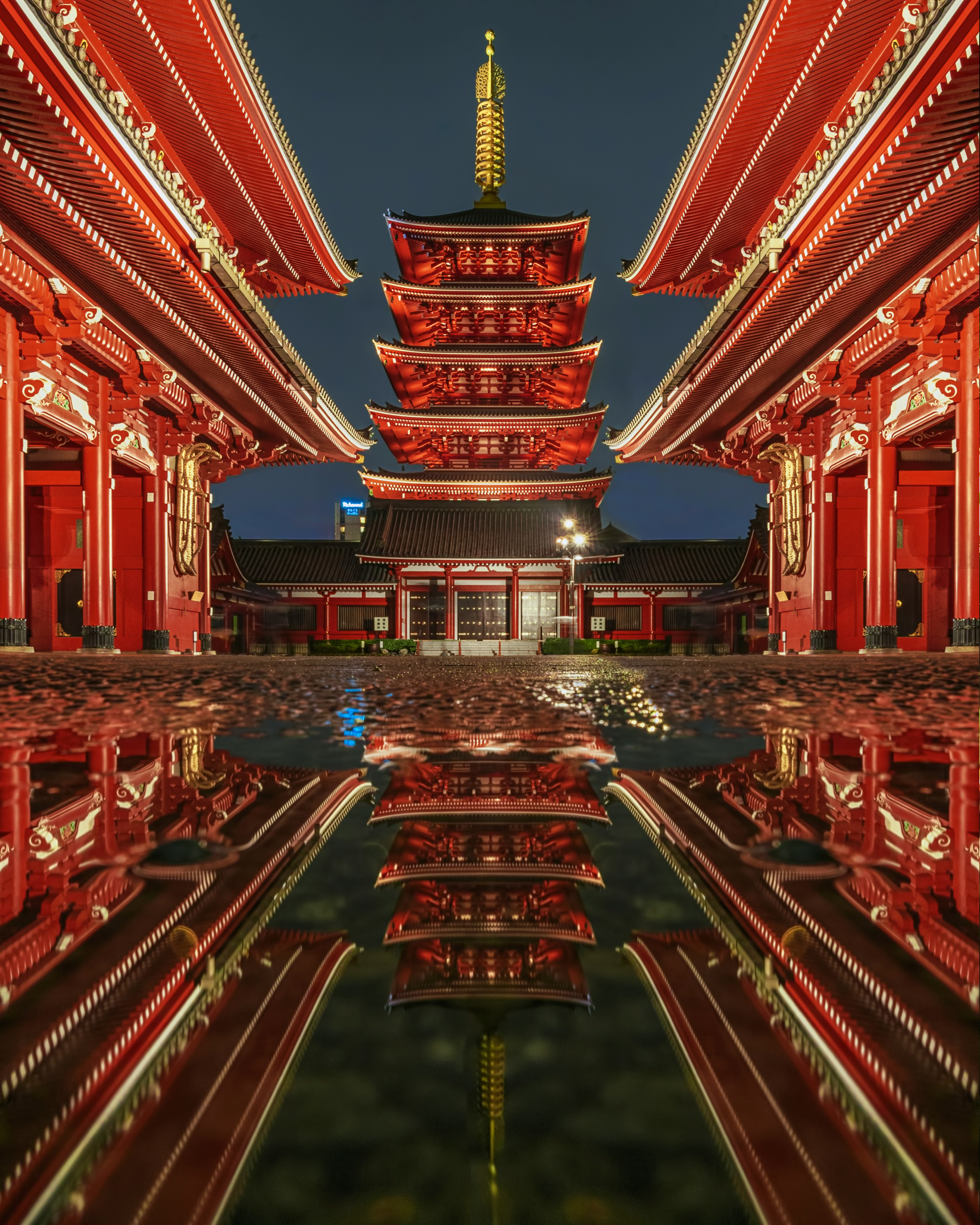 Beautiful reflection of the Sensoji Temple's pagoda and red buildings at night