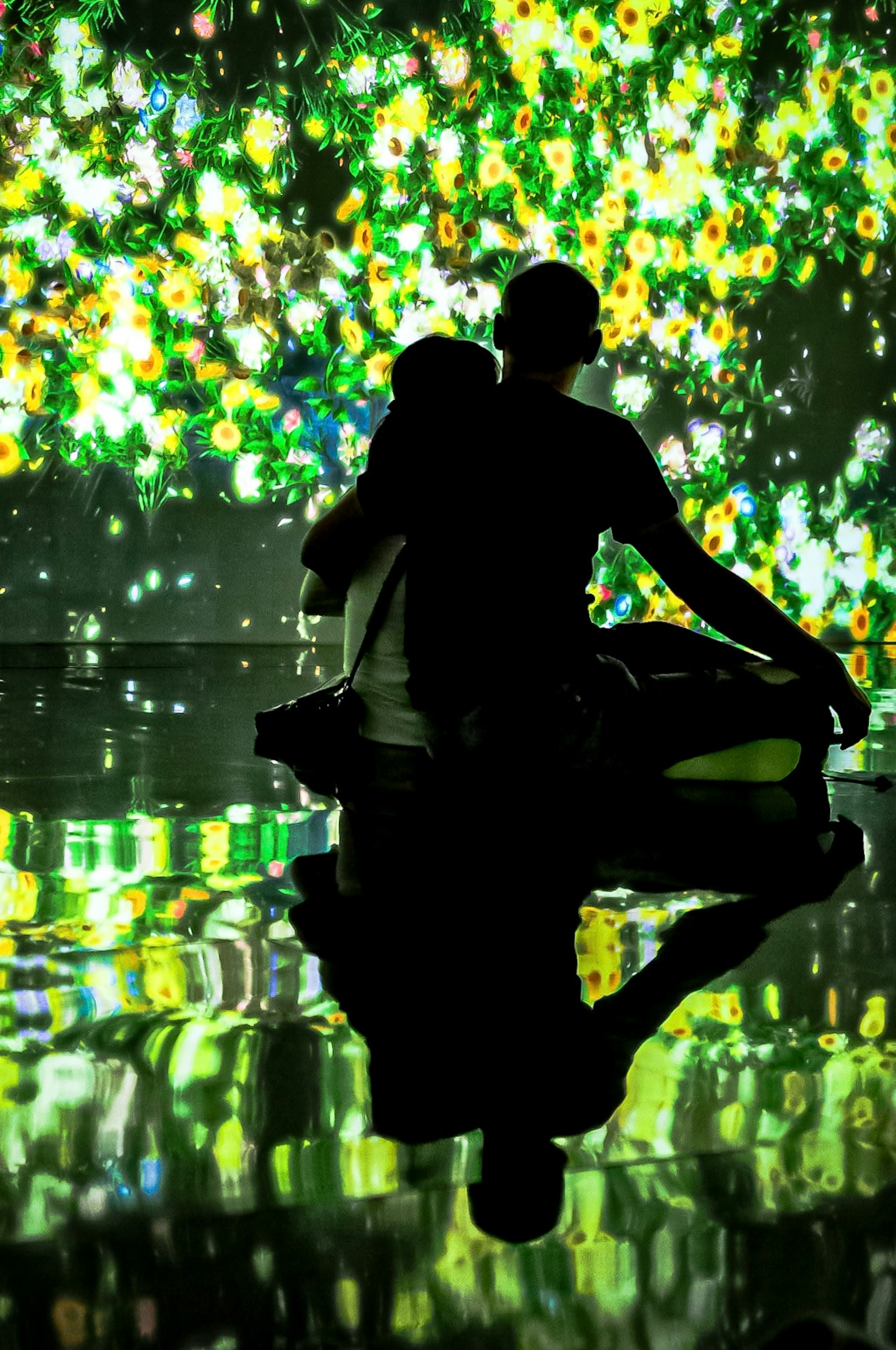 Silhouette d'un couple assis devant un mur affichant des visuels floraux verts