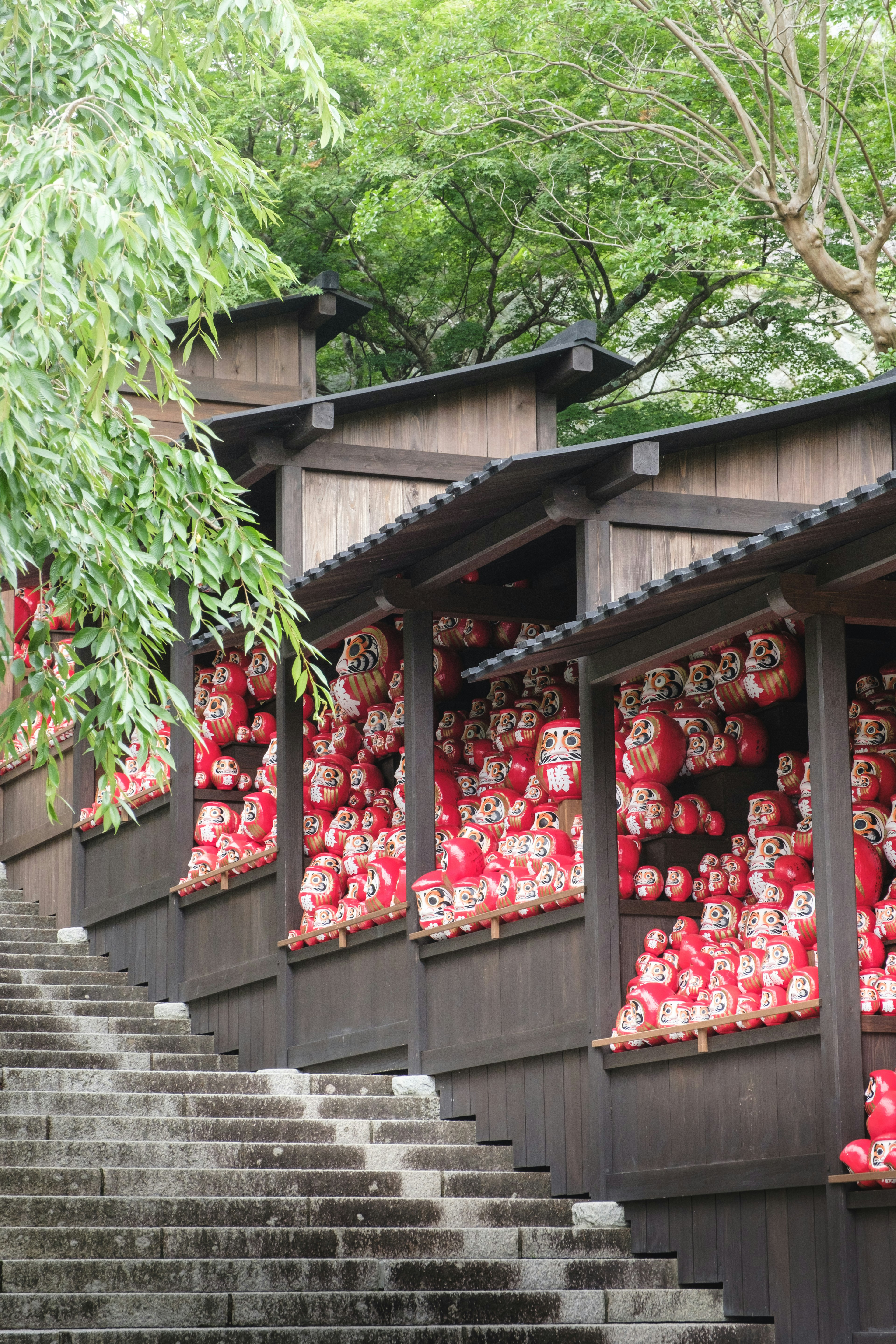 赤い提灯が並ぶ木造の建物と石の階段がある風景