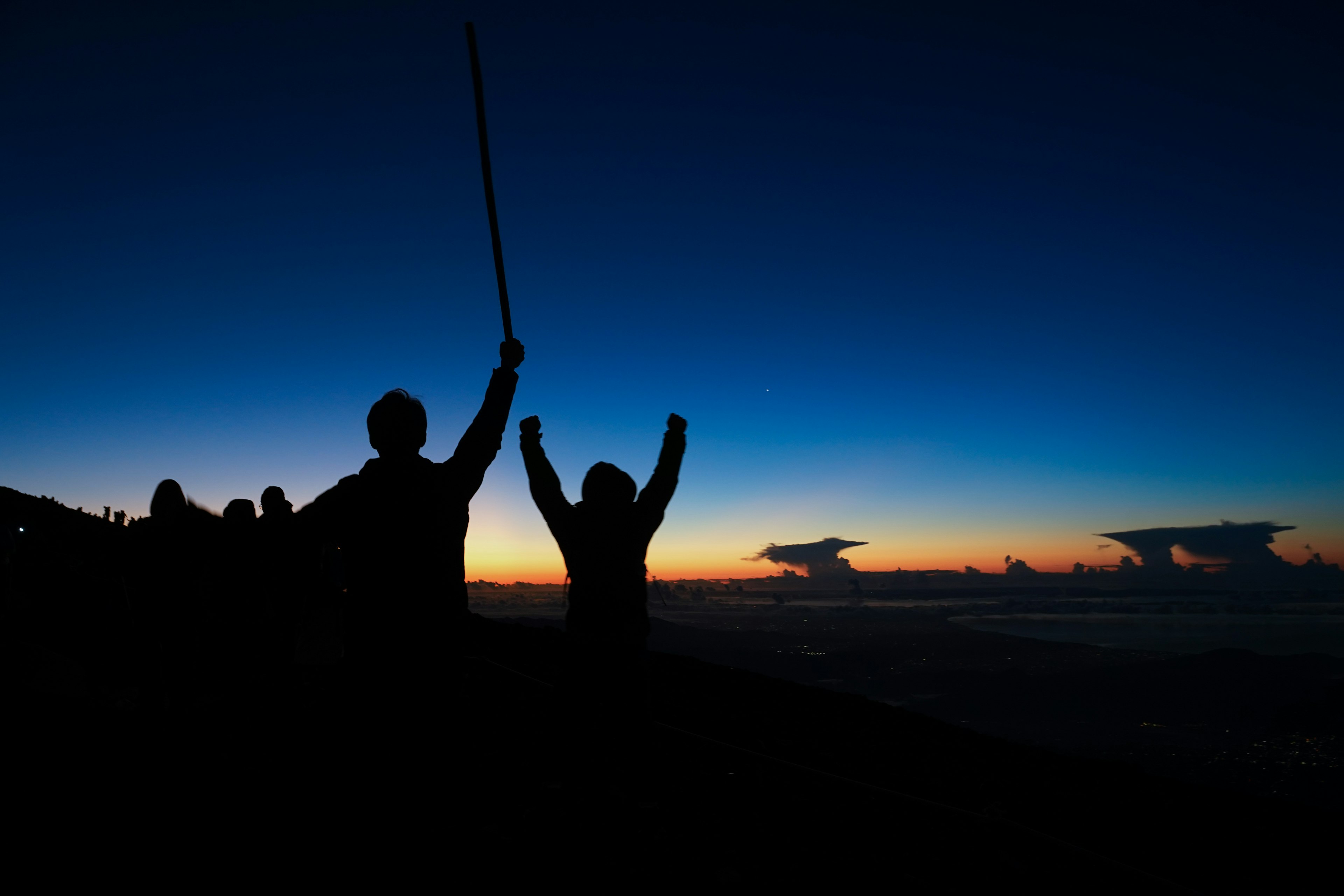 Silueta de dos personas celebrando contra un fondo de atardecer