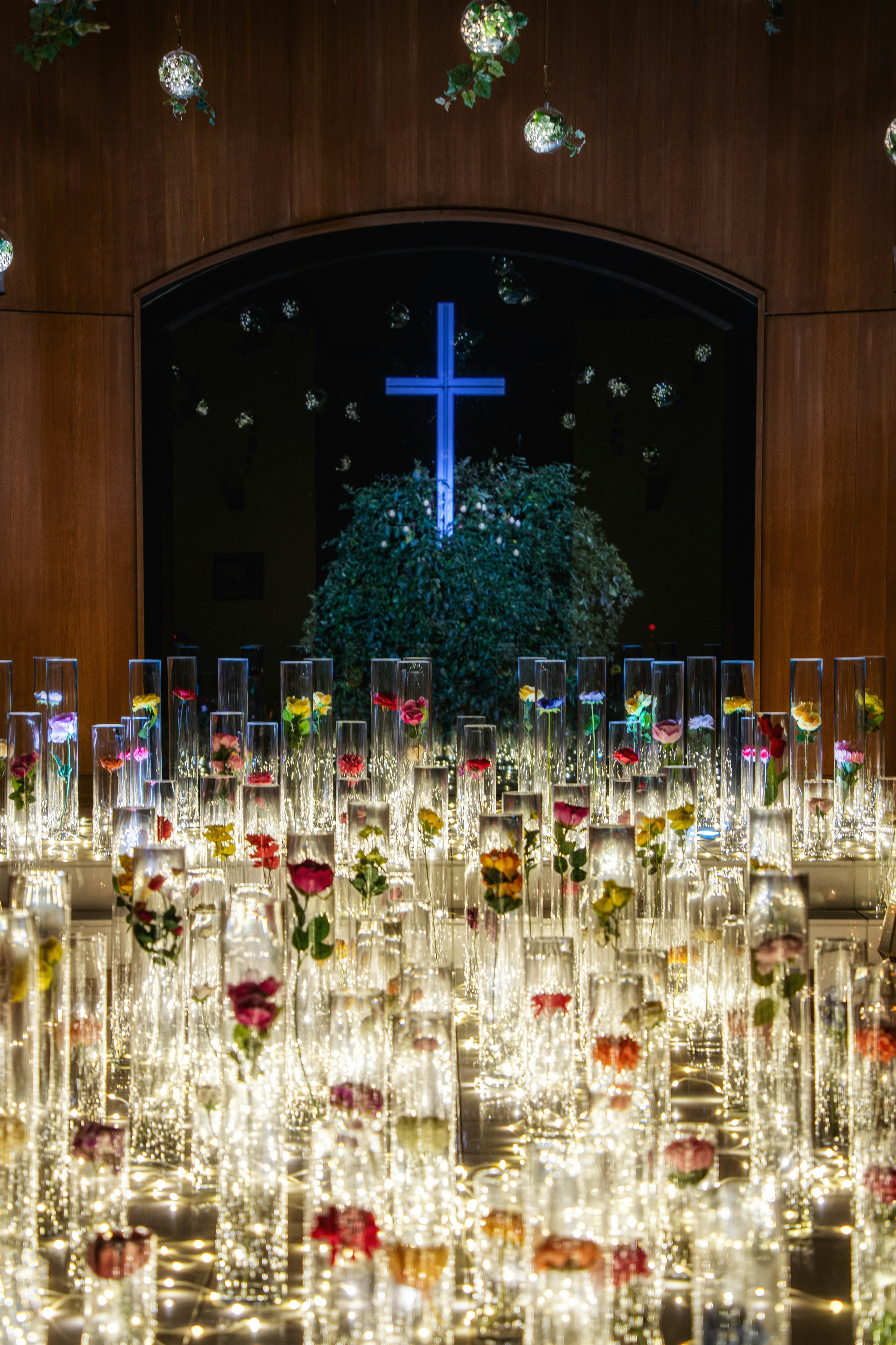 Beautiful altar with blue cross and illuminated vases filled with flowers