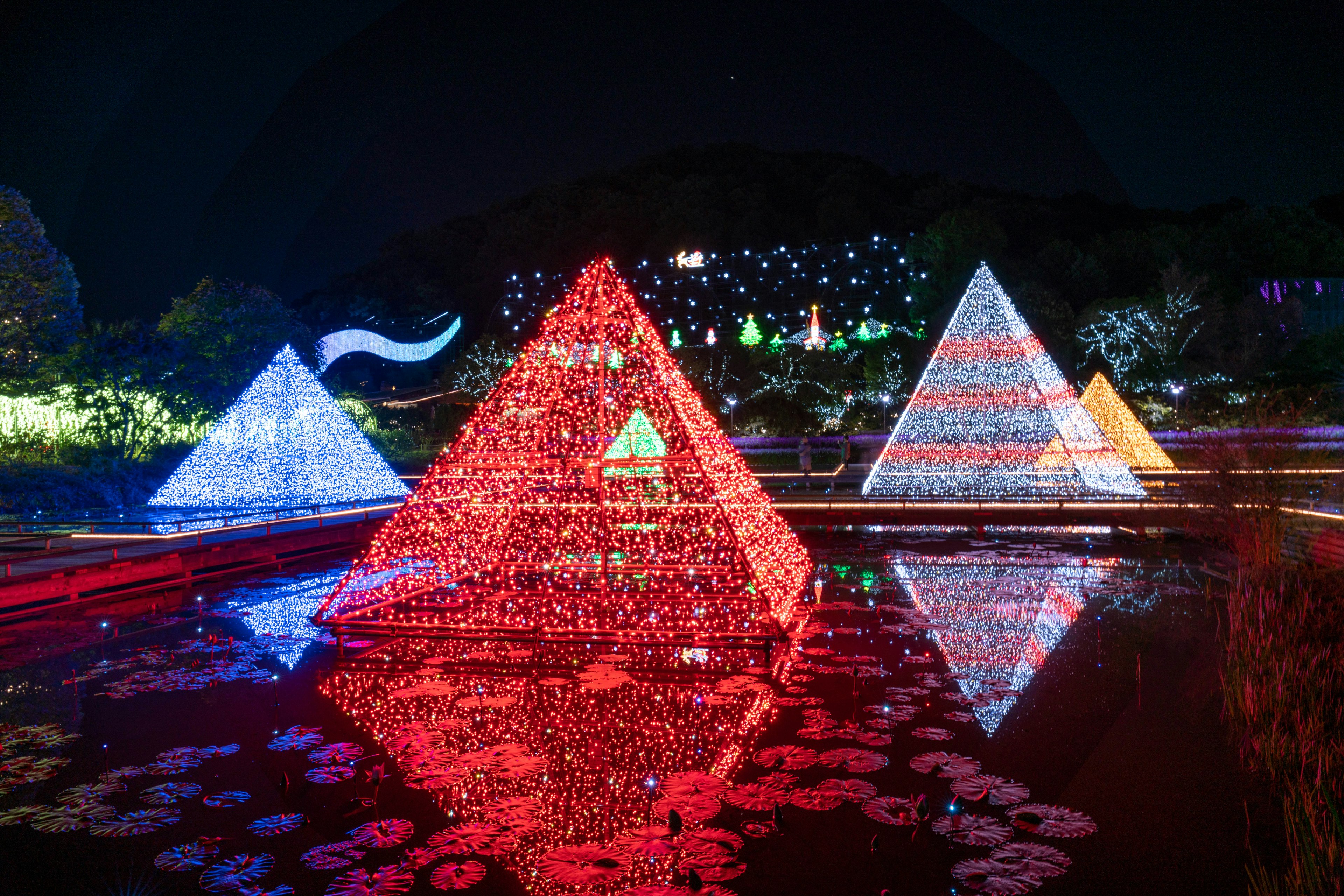 Pirámides iluminadas de colores reflejándose en un estanque nocturno