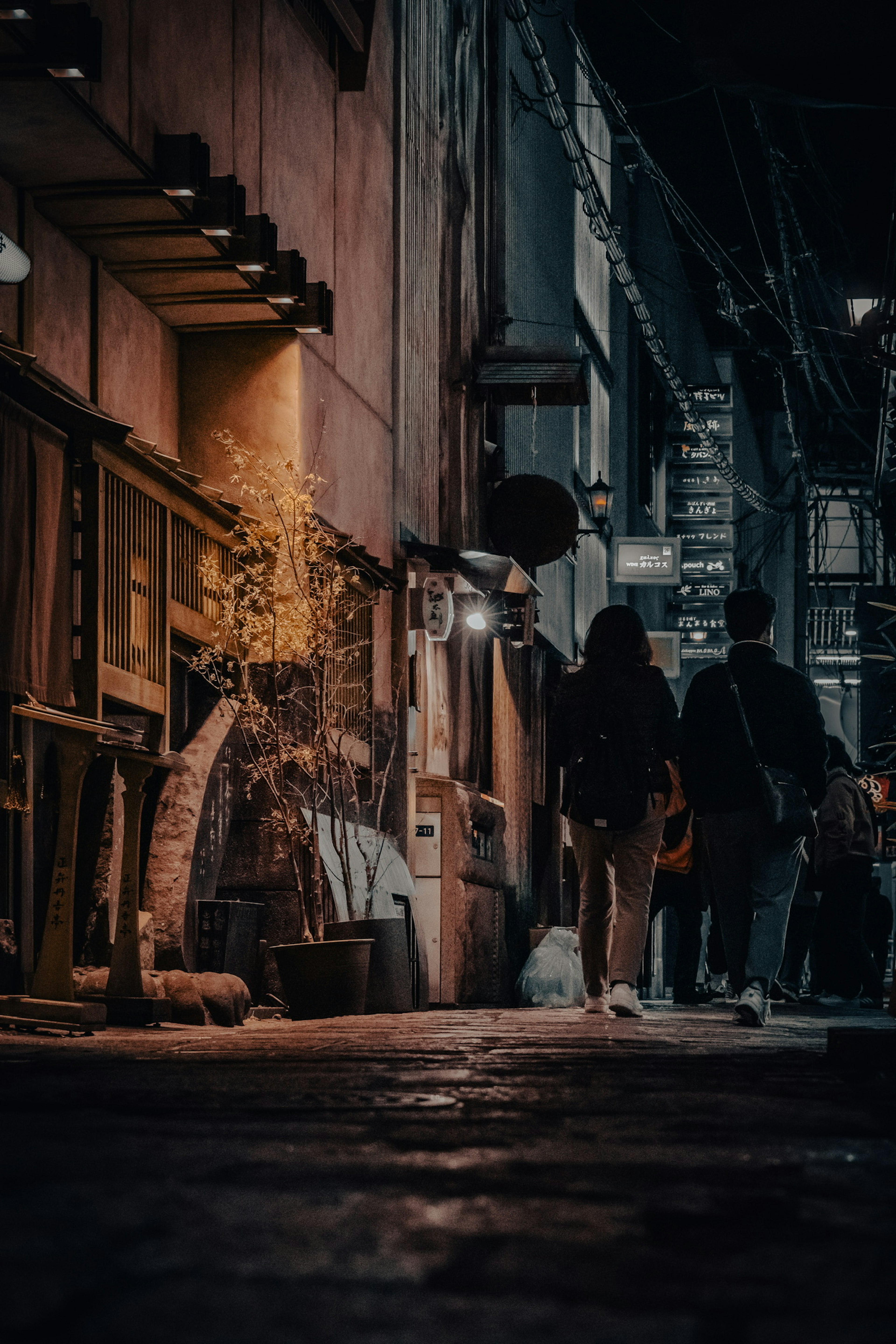 People walking in a dimly lit alley with illuminated shops