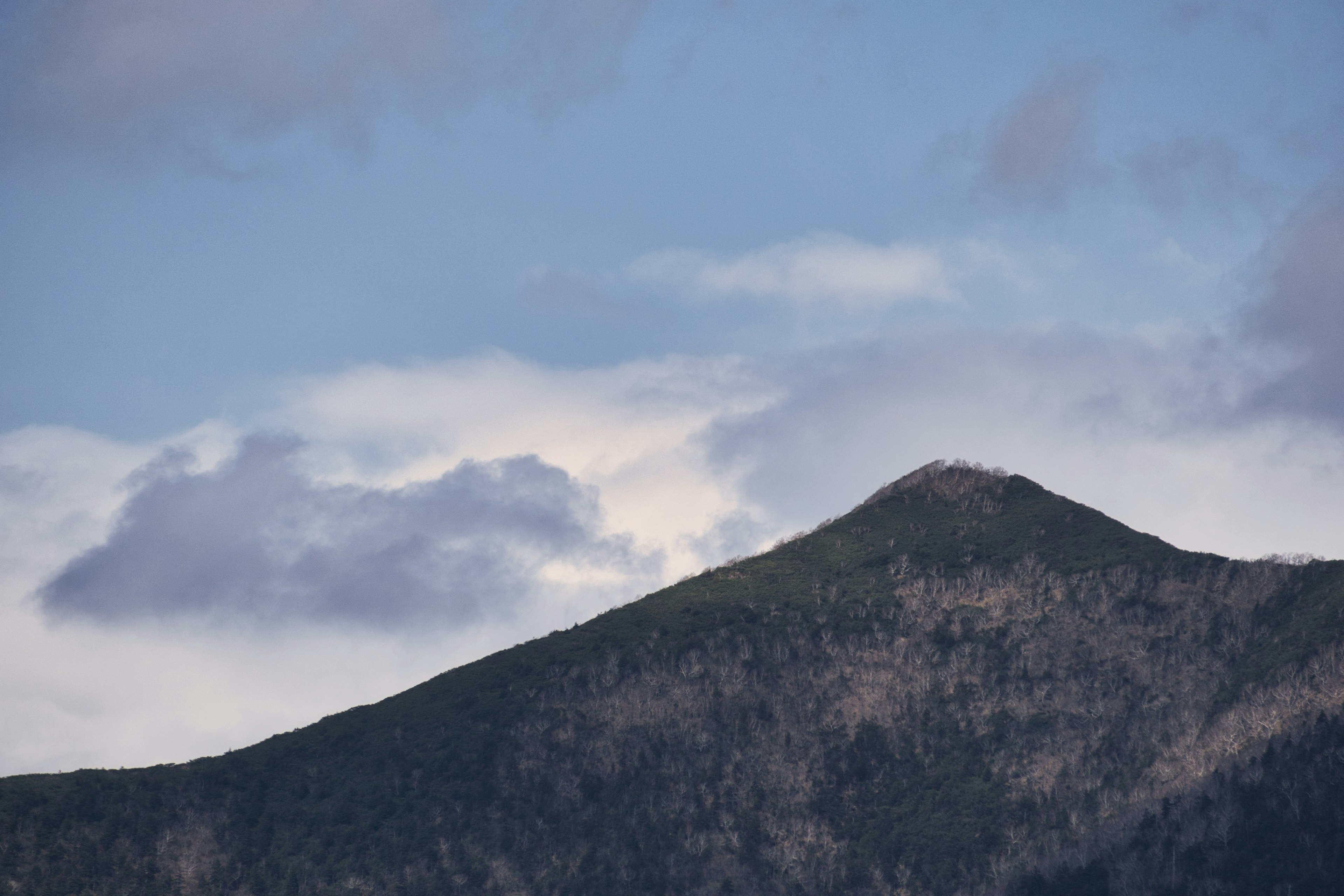 Cima de montaña bajo un cielo azul con nubes