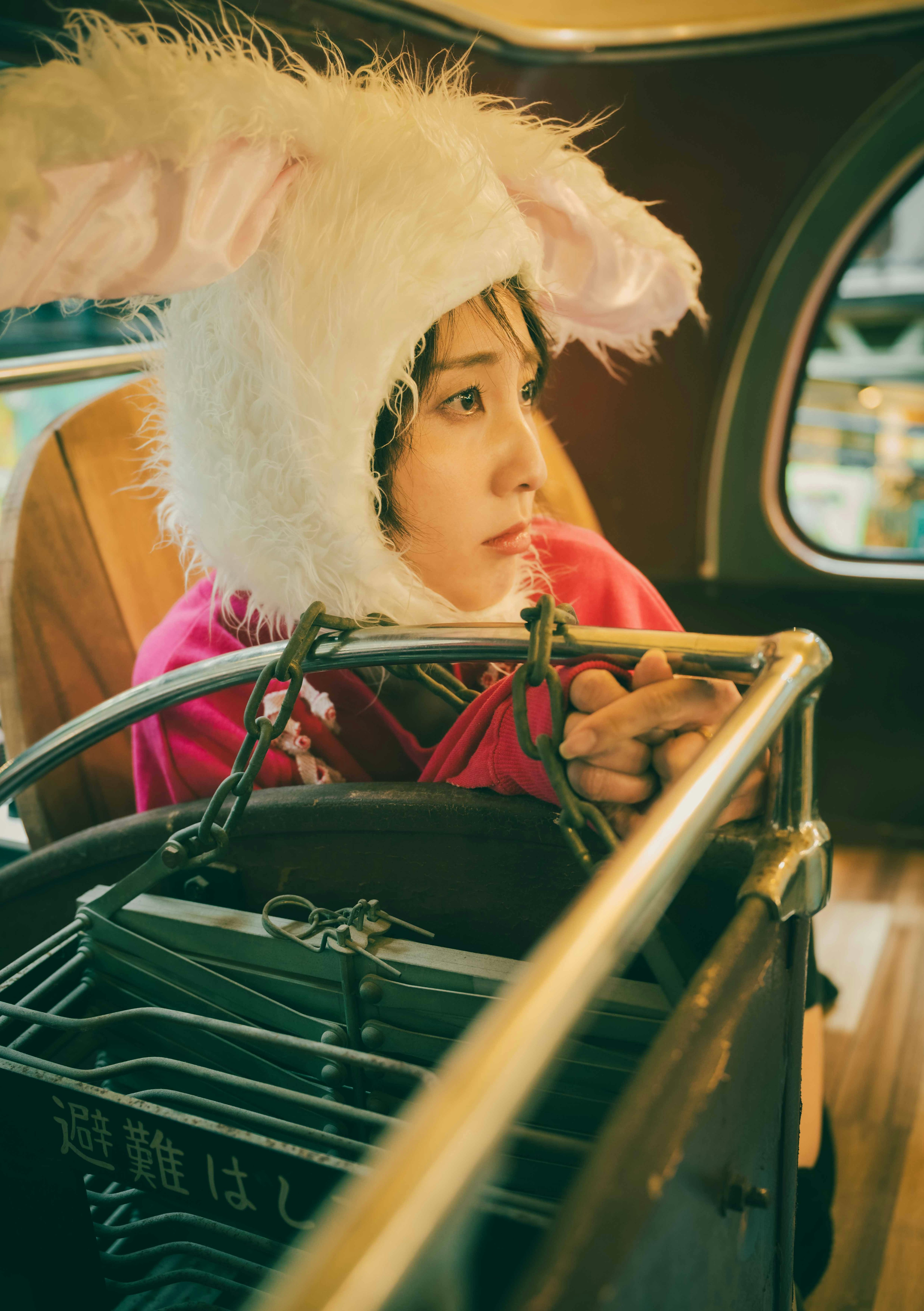 Girl wearing a bunny hat sitting on a bus looking thoughtful