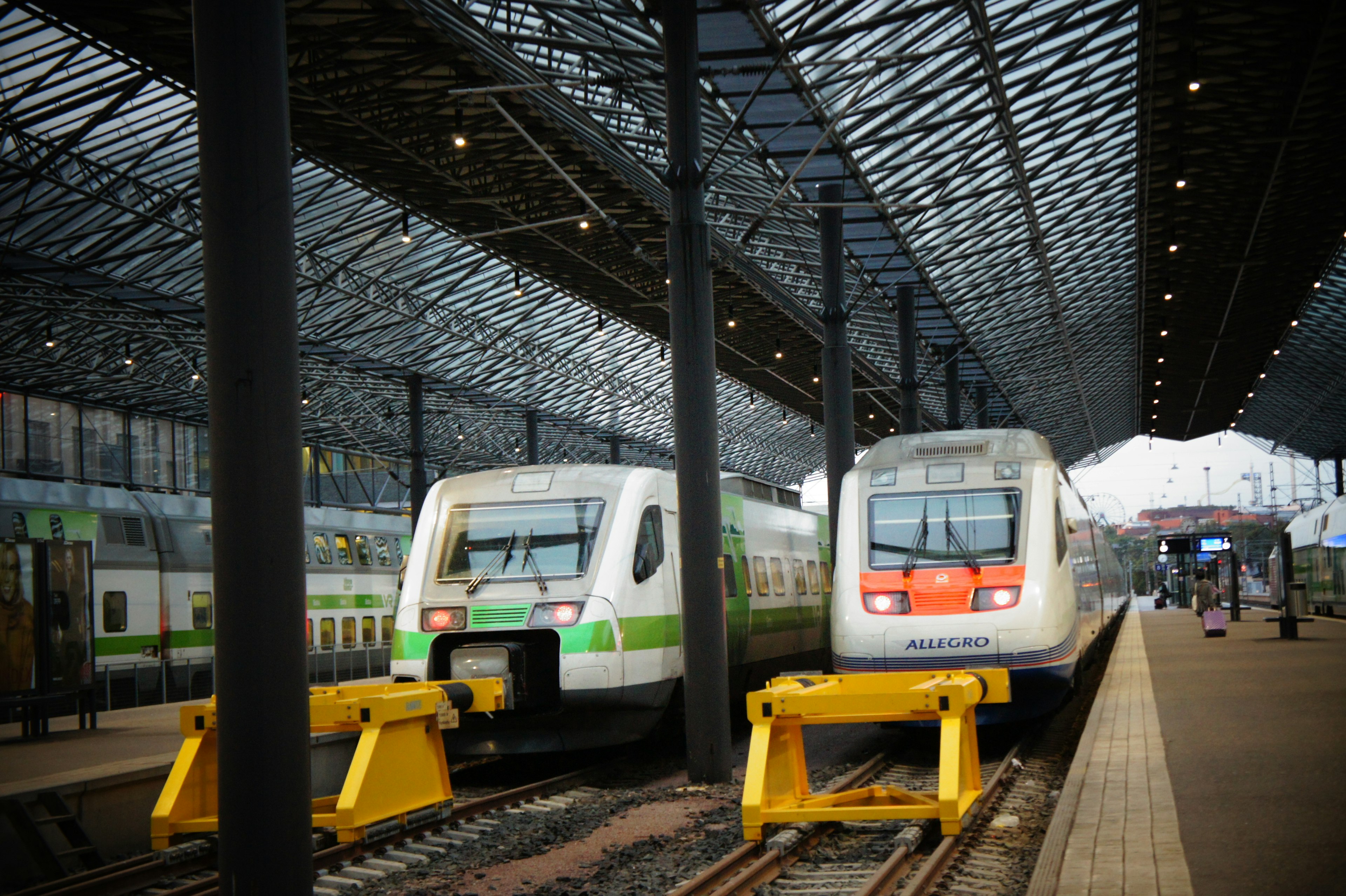 Deux trains stationnés dans une gare moderne avec un toit en verre