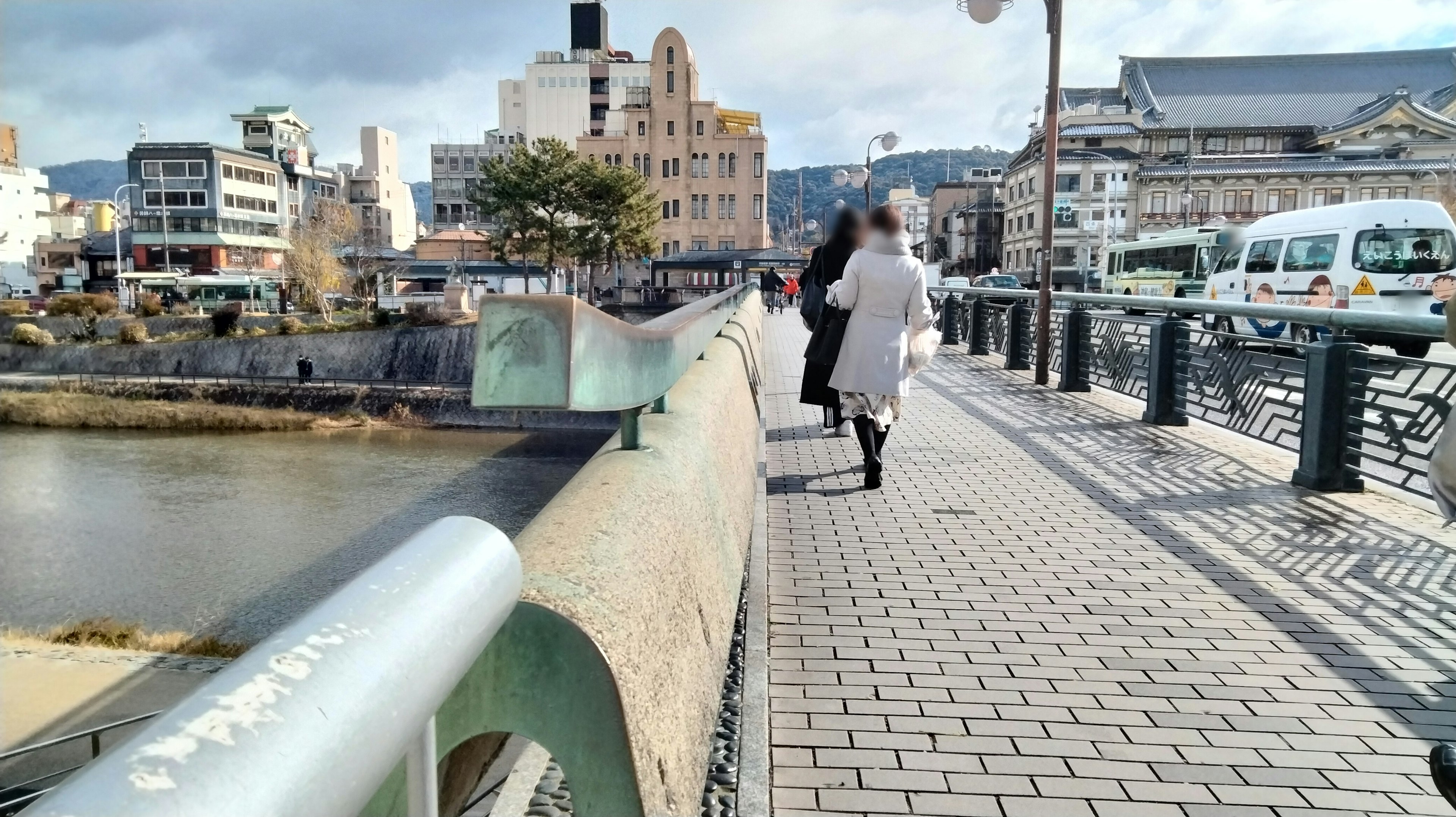 People walking along a riverside walkway with modern buildings