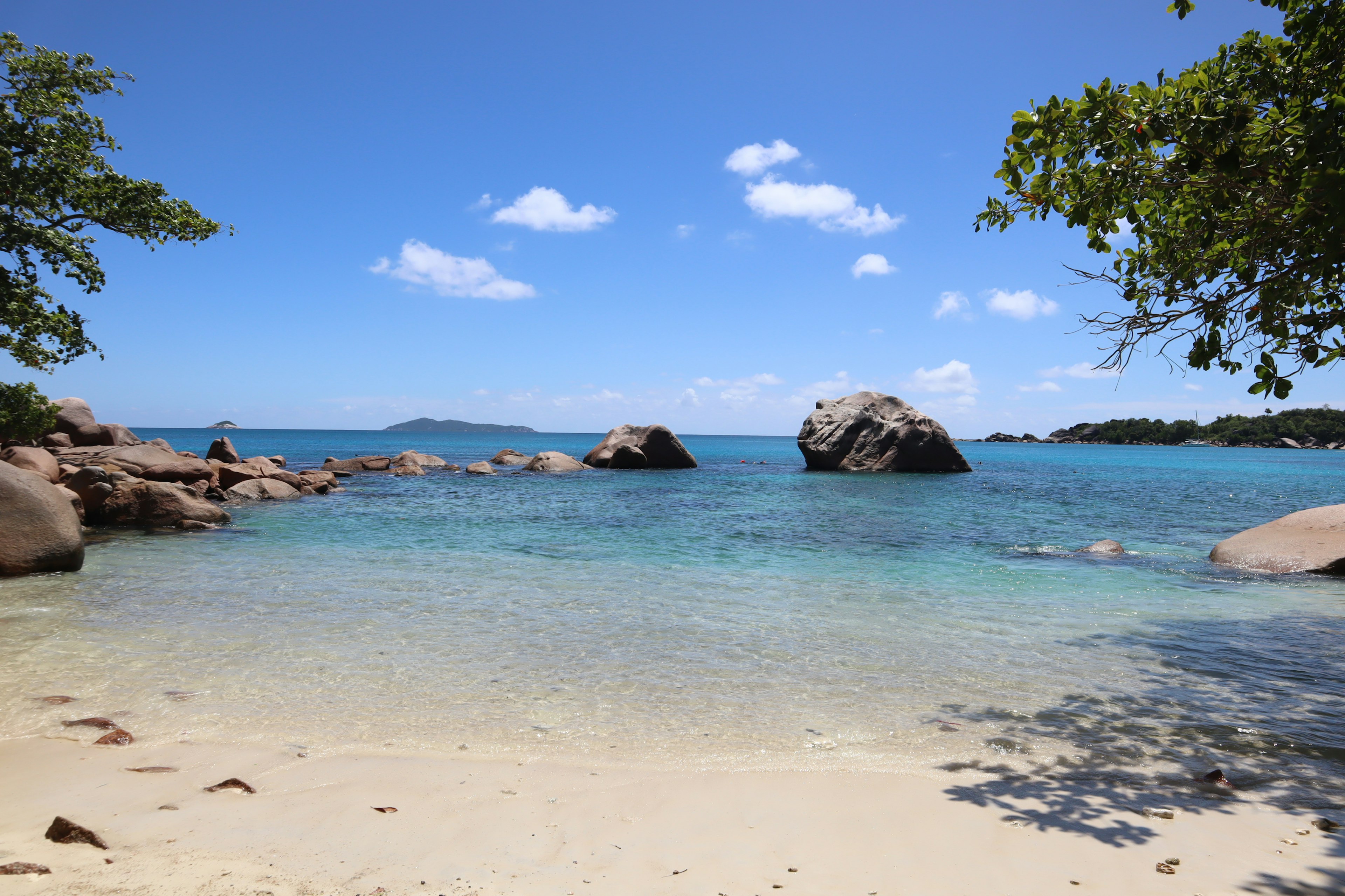 Pantai indah dengan air pirus dan batu besar di bawah langit biru yang cerah