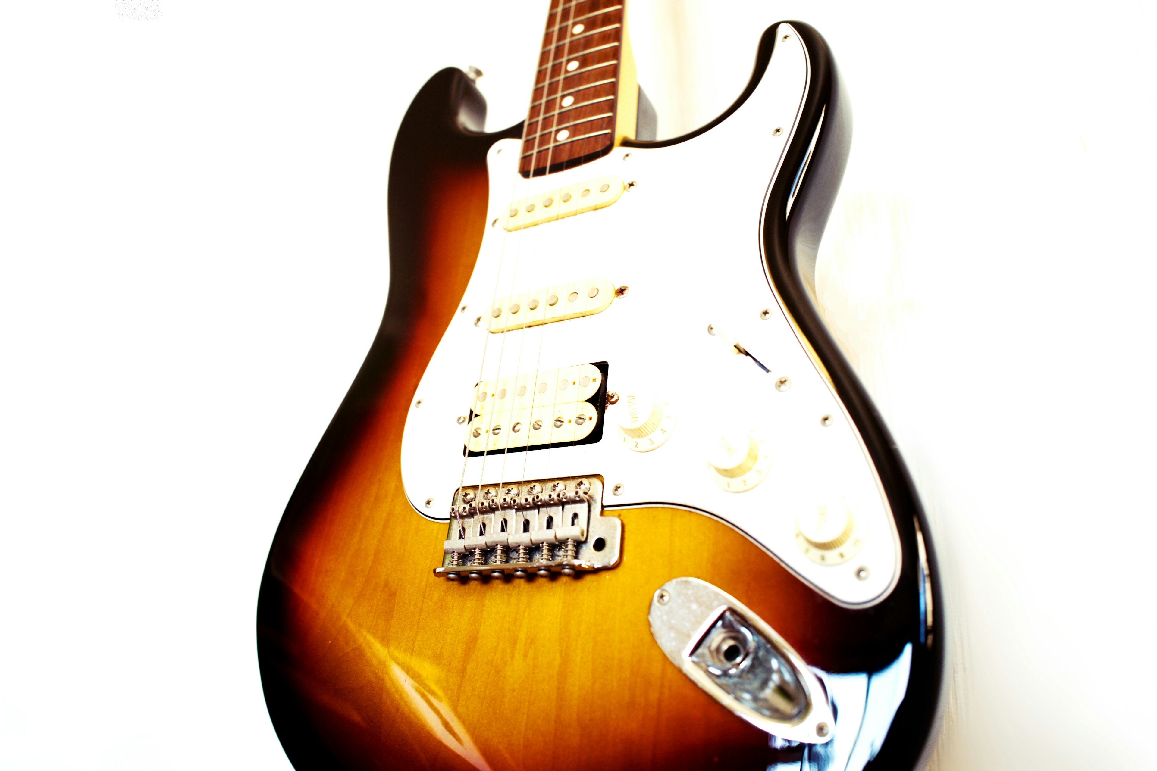 Close-up of an electric guitar with sunburst color set against a white background