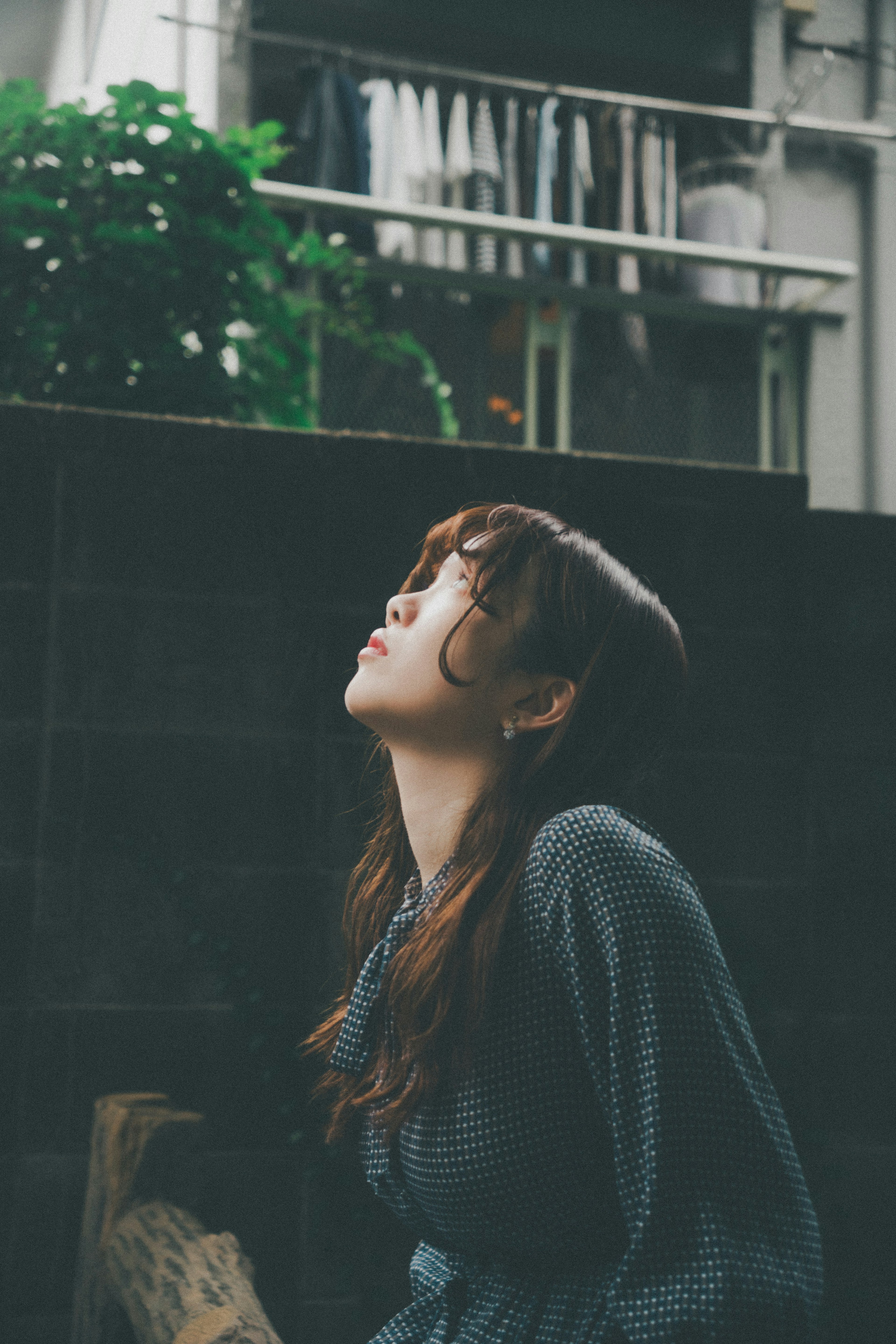 女性が上を向いている姿と背景の緑の植物