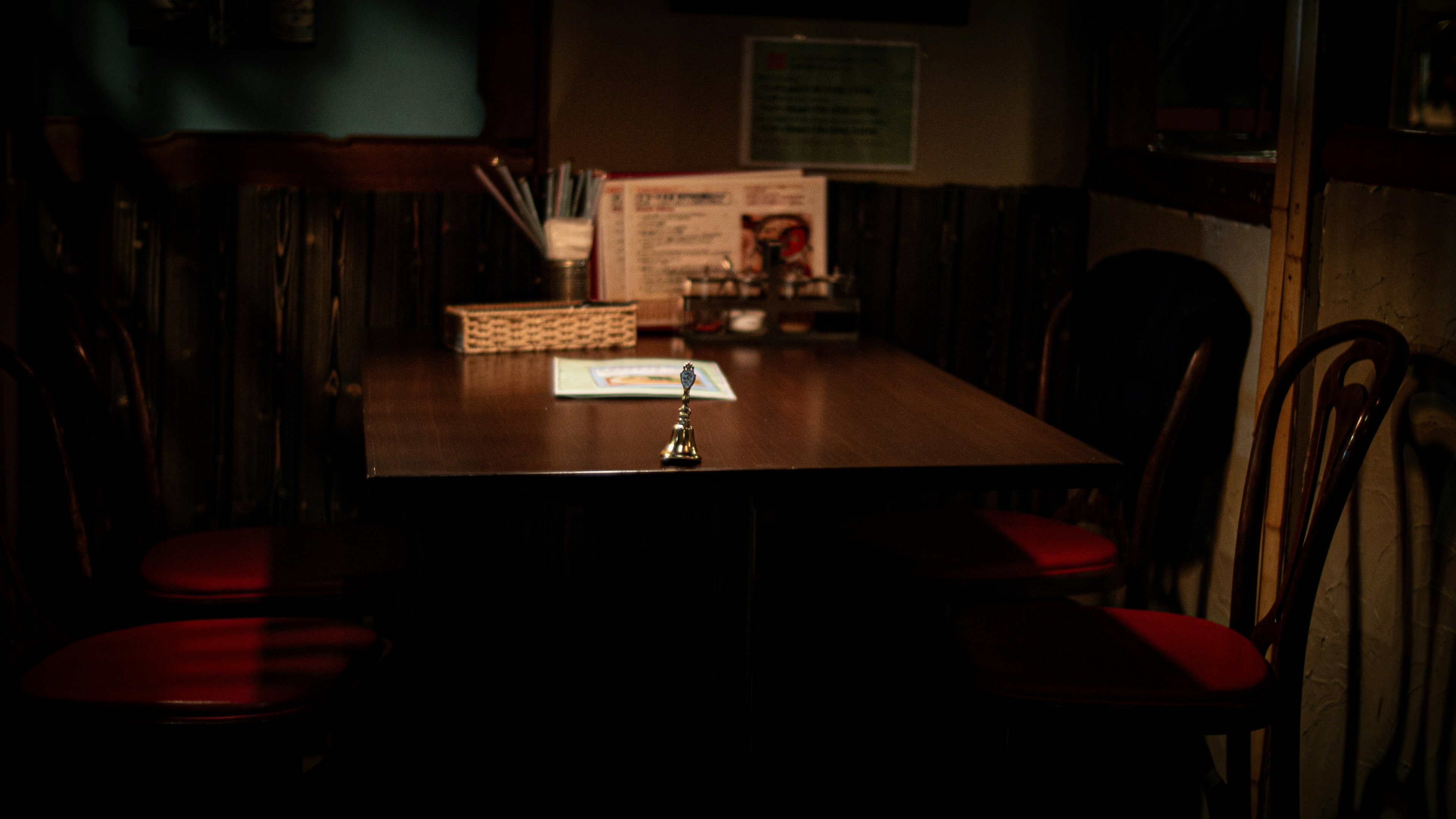 Dimly lit restaurant table with red chairs and a menu