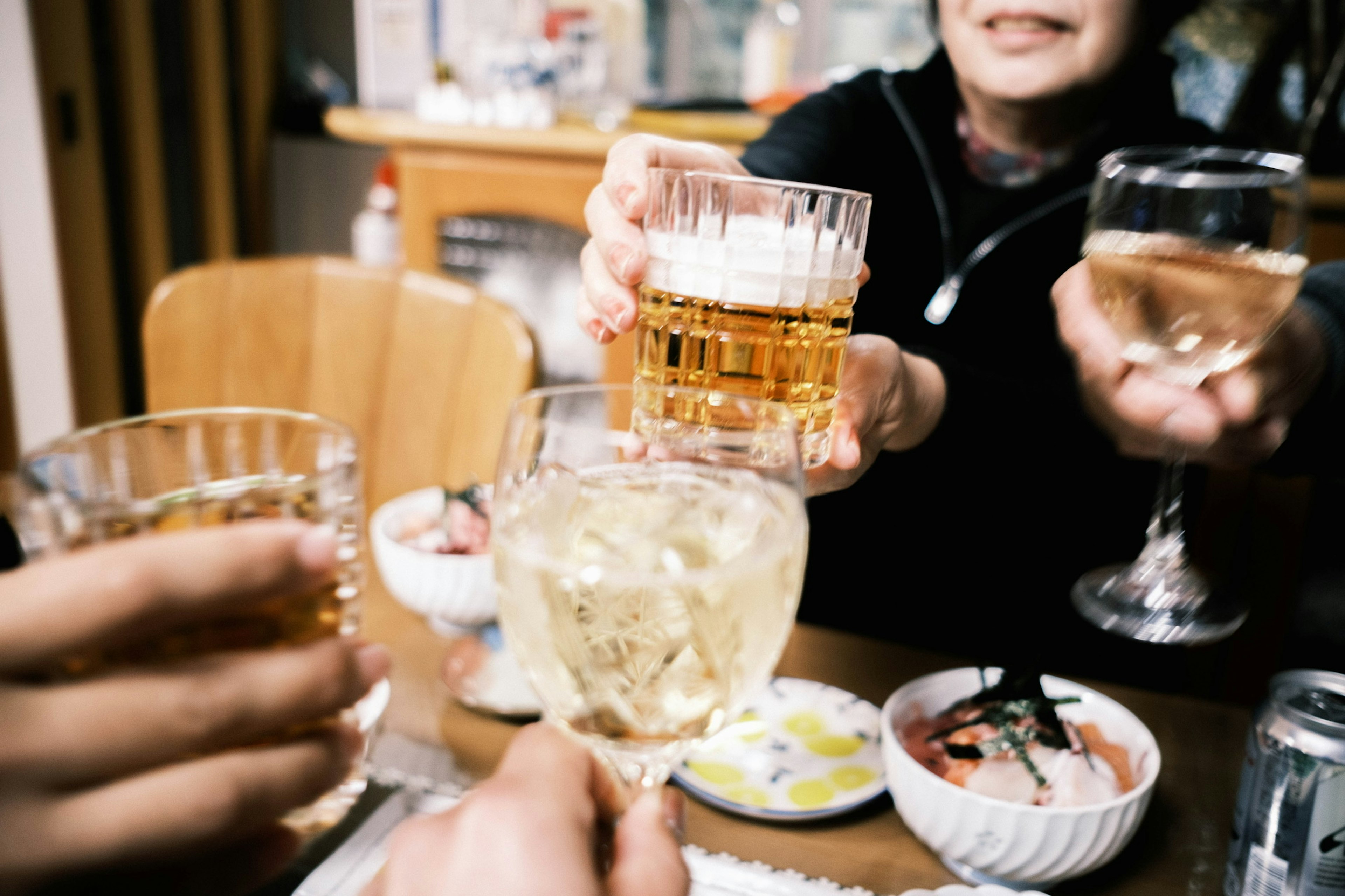 A scene of hands holding glasses for a toast around a table