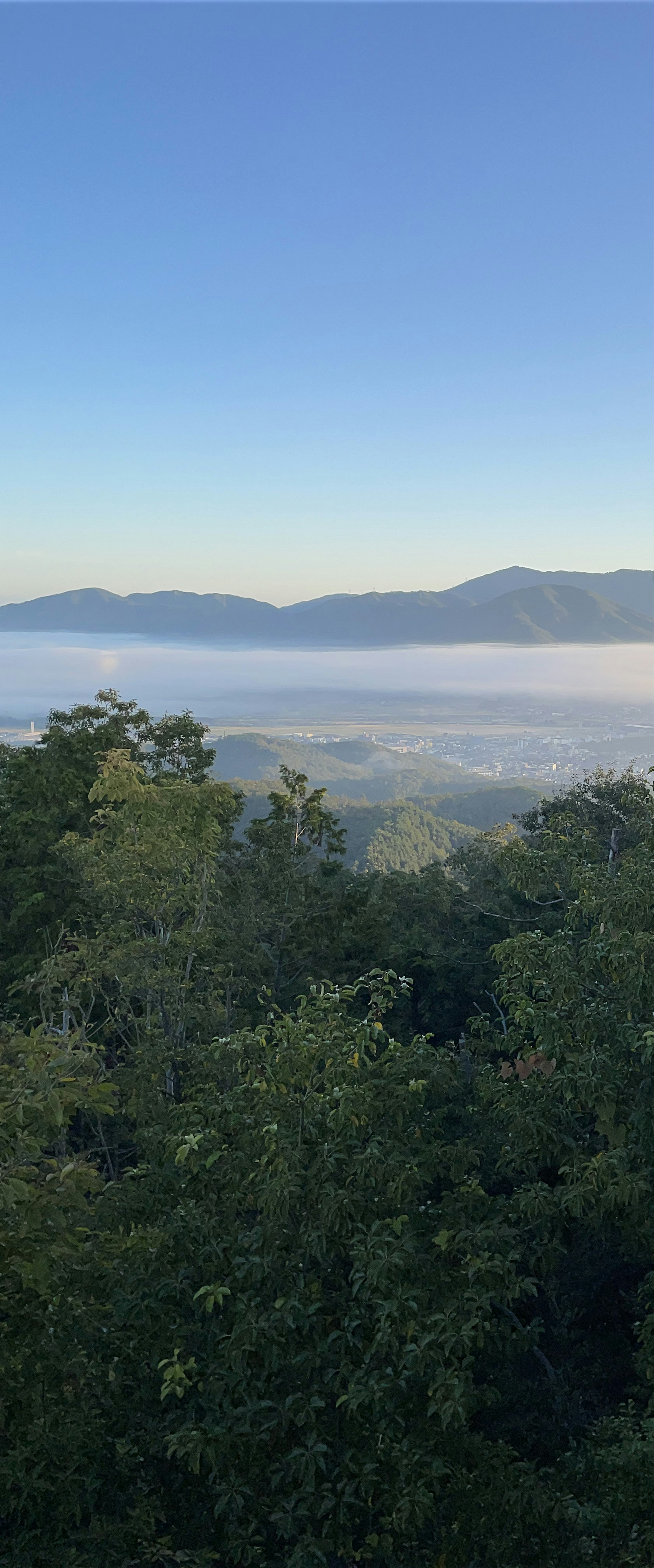 Vista escénica de un valle brumoso con montañas bajo un cielo azul