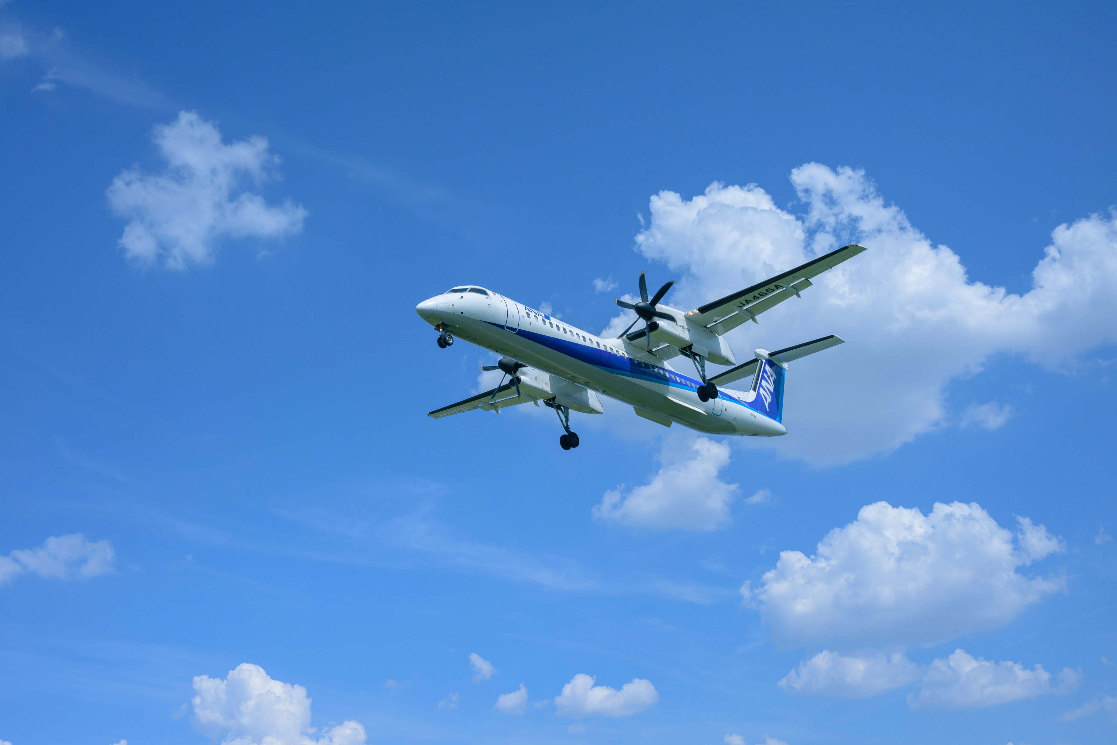 Propeller aircraft flying in a blue sky with white clouds