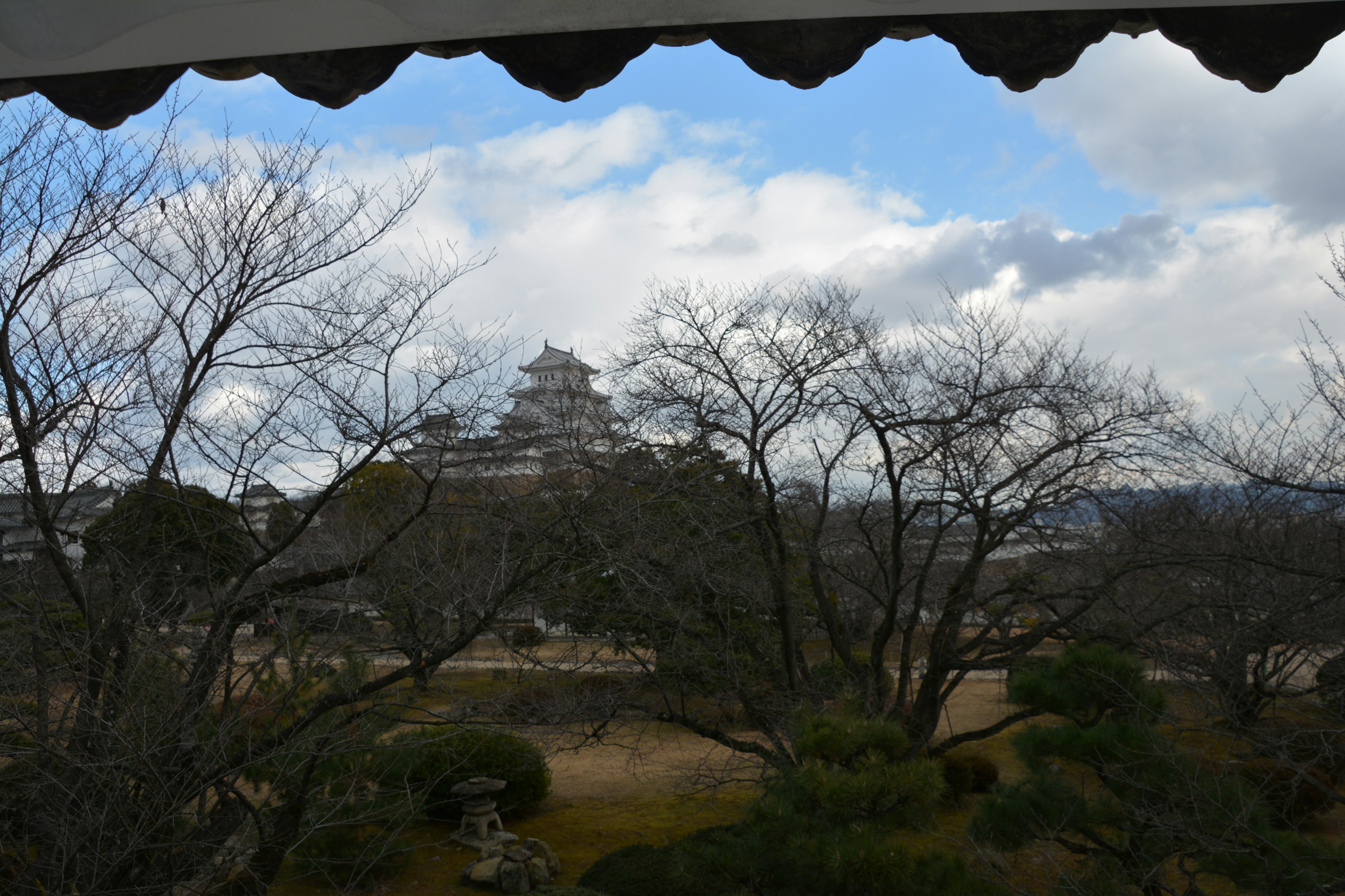 Vista lejana del castillo de Himeji enmarcado por árboles sin hojas